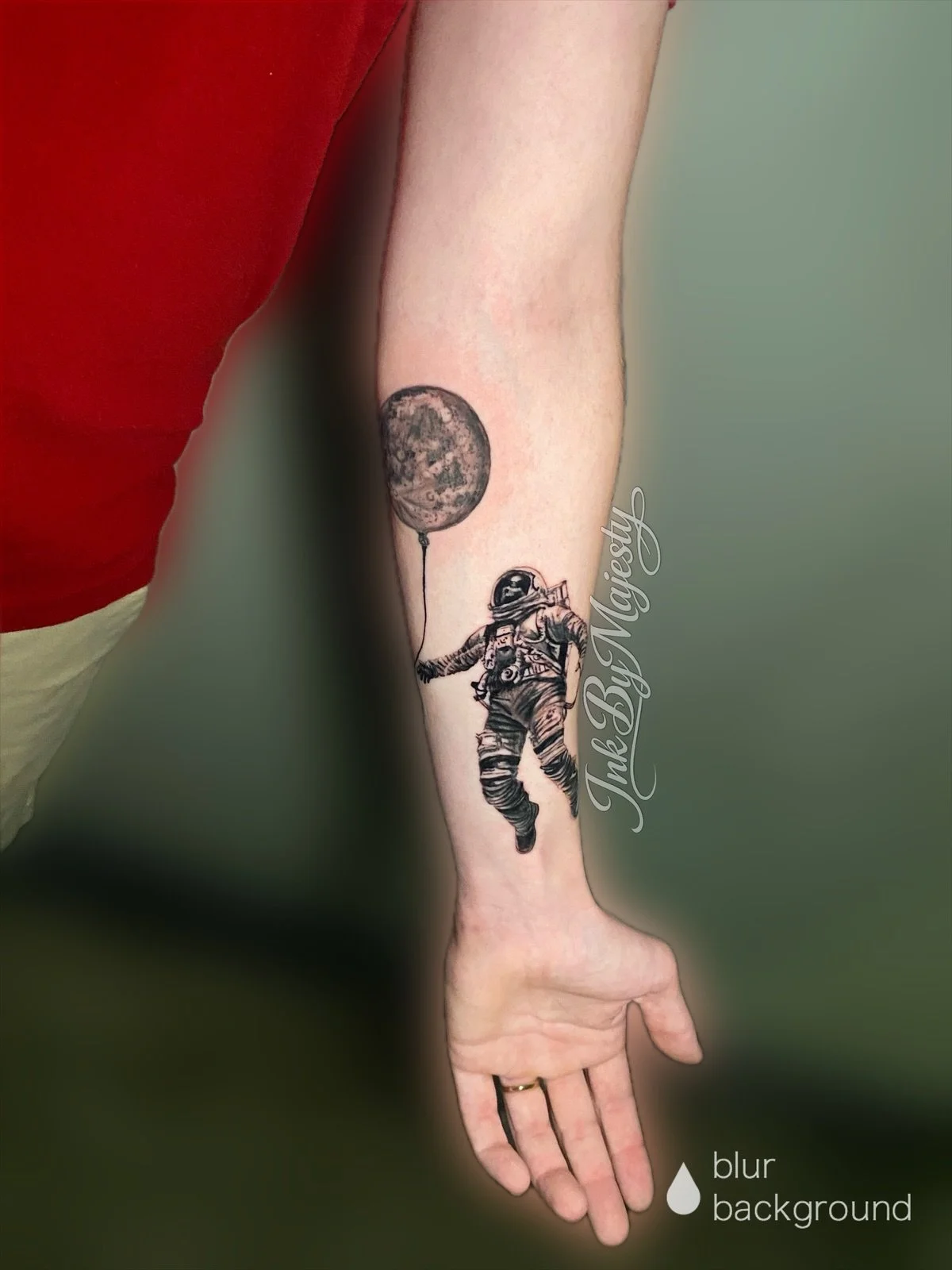 Tattoo of an astronaut holding a balloon shaped like the moon on a person's inner arm.
