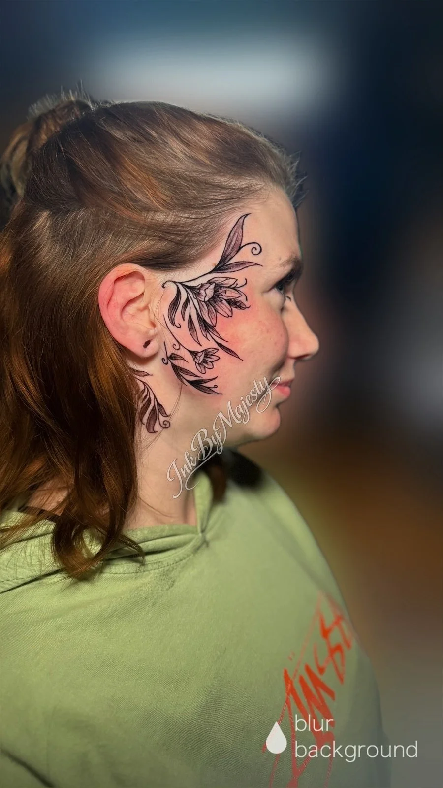 Side profile of a young woman with a floral tattoo on her face around her left eye.