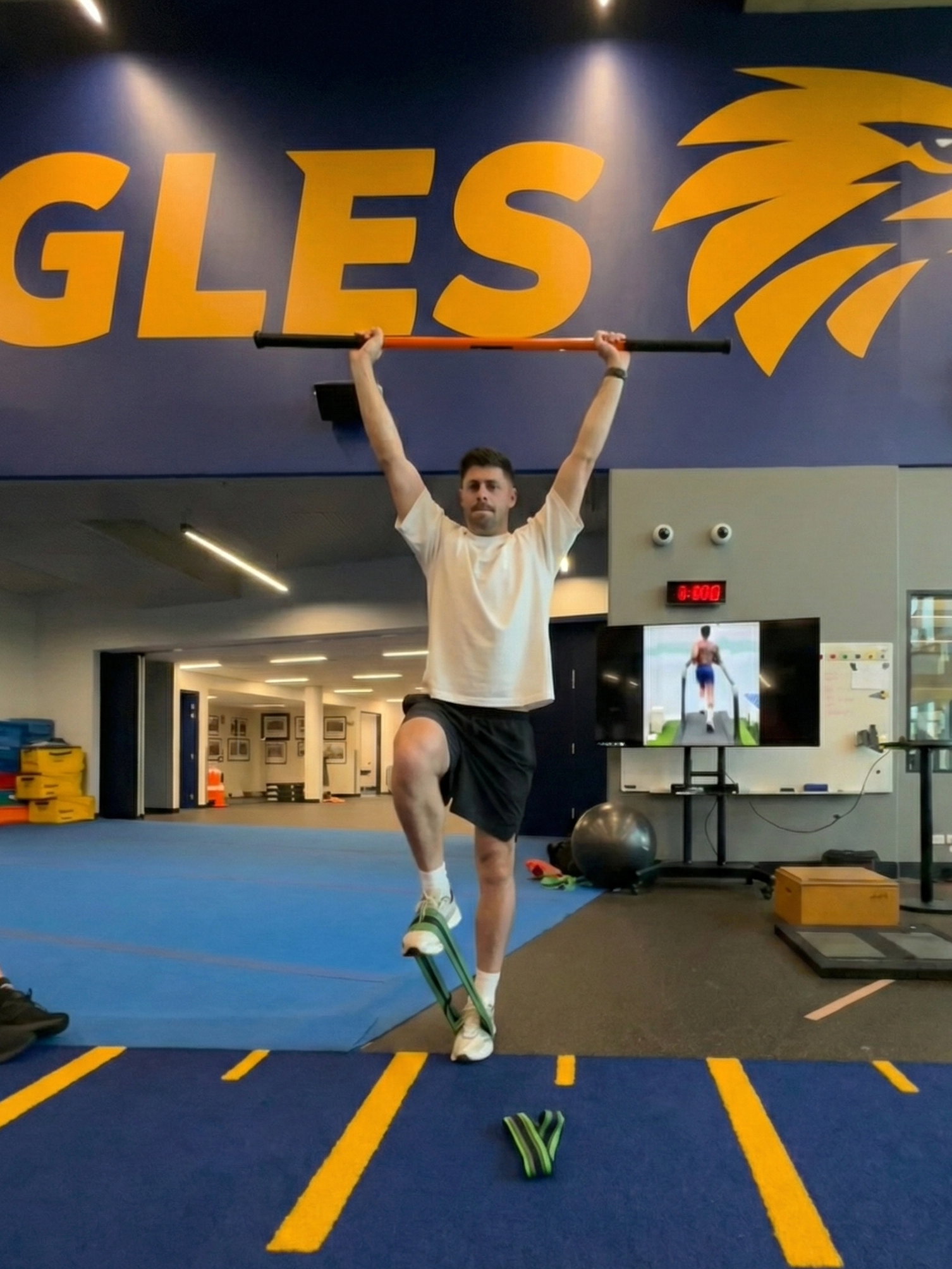 Athlete at Macarthur Physiotherapy performing a single-leg overhead reach to test stability and force production.