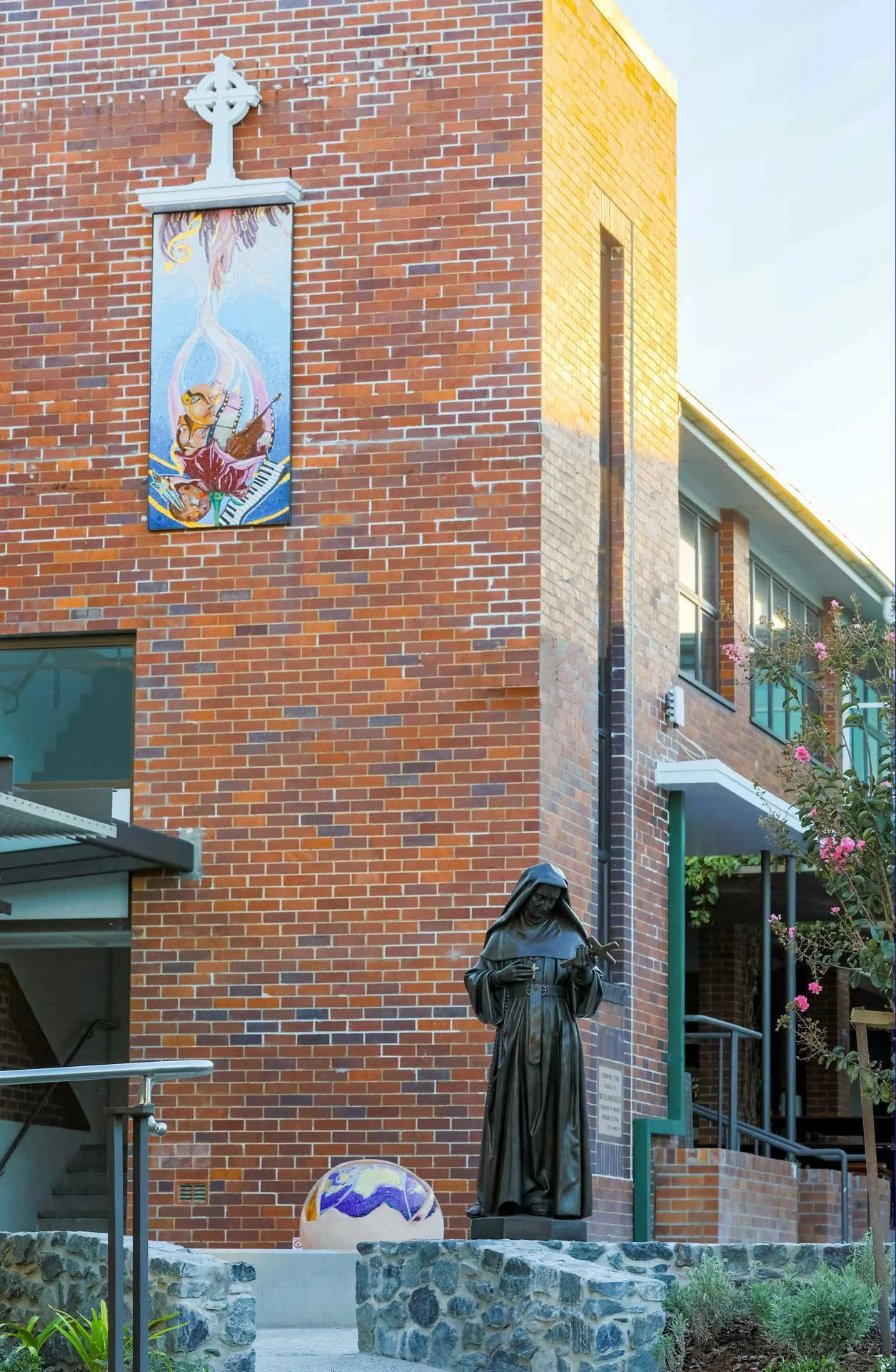 The St Rita's College Trinity Centre greets visitors with a stunning hand-carved sandstone sculpture of the Earth, adorned with Orsoni smalti and gold leaf tesserae. 
