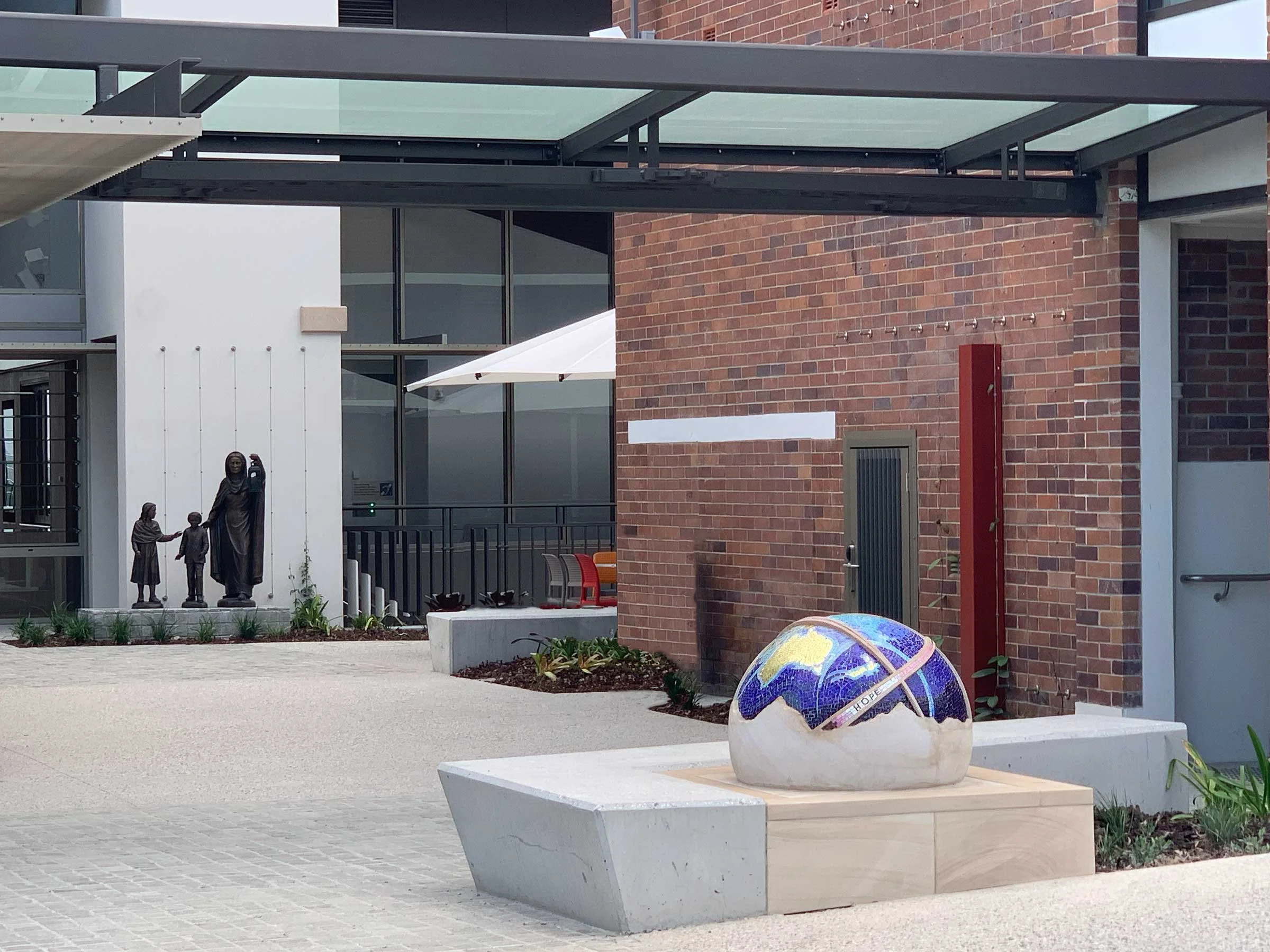 The St Rita's College Trinity Centre greets visitors with a stunning hand-carved sandstone sculpture of the Earth, adorned with Orsoni smalti and gold leaf tesserae. 