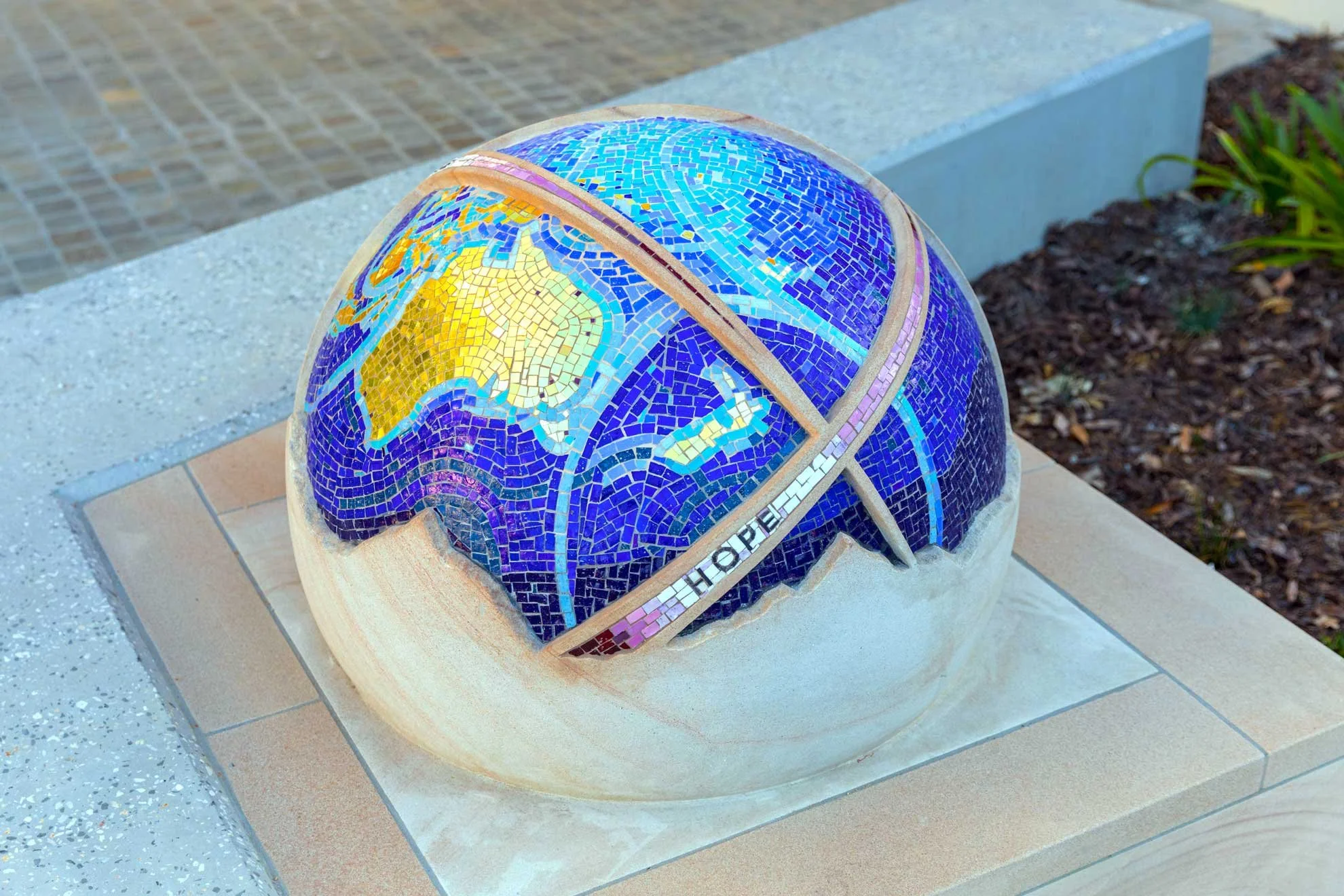The St Rita's College Trinity Centre greets visitors with a stunning hand-carved sandstone sculpture of the Earth, adorned with Orsoni smalti and gold leaf tesserae. 