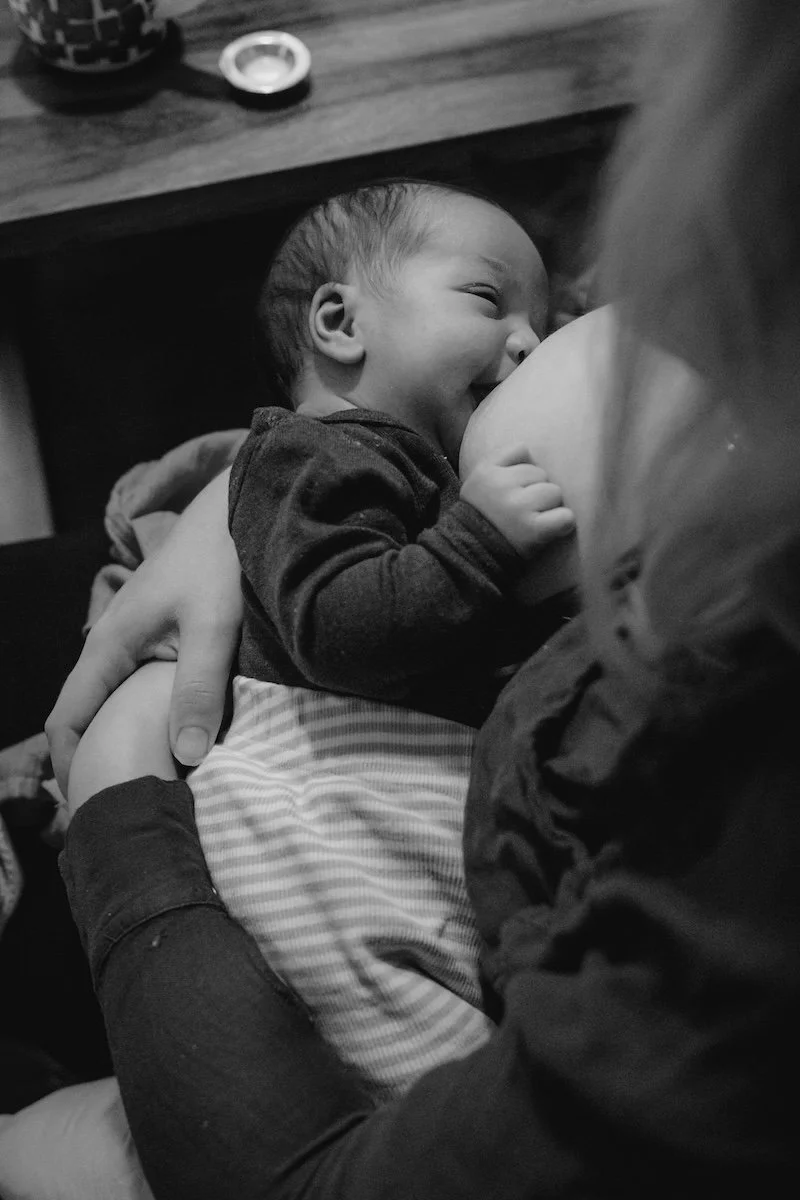 Eine Mama hält ihr Neugeborenes im Arm und stillt es.