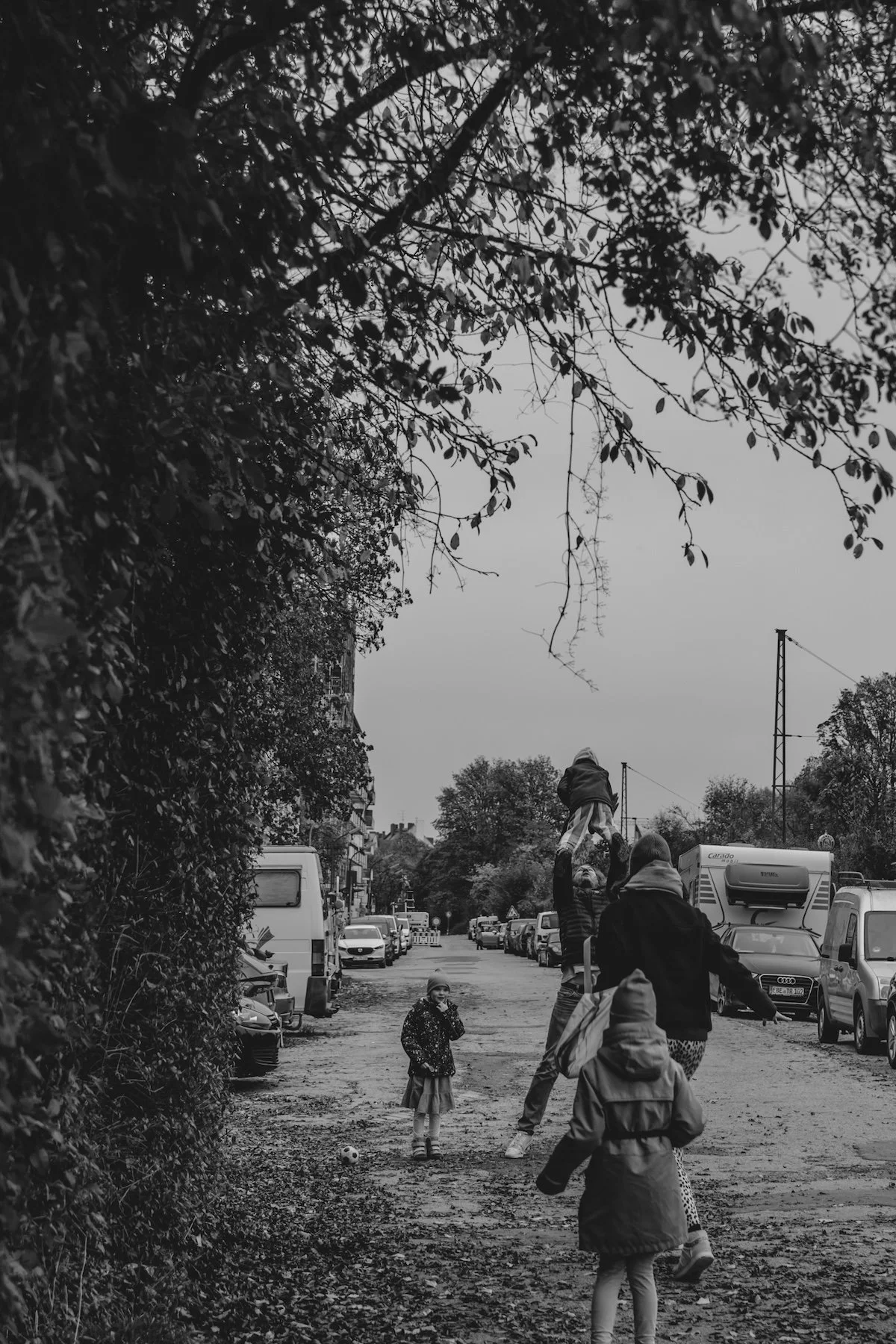 Die Tochter und Mama rennen auf den Papa zu, welcher gerade das jüngste Kind in die Luft wirft, daneben steht lachend die andere Tochter.