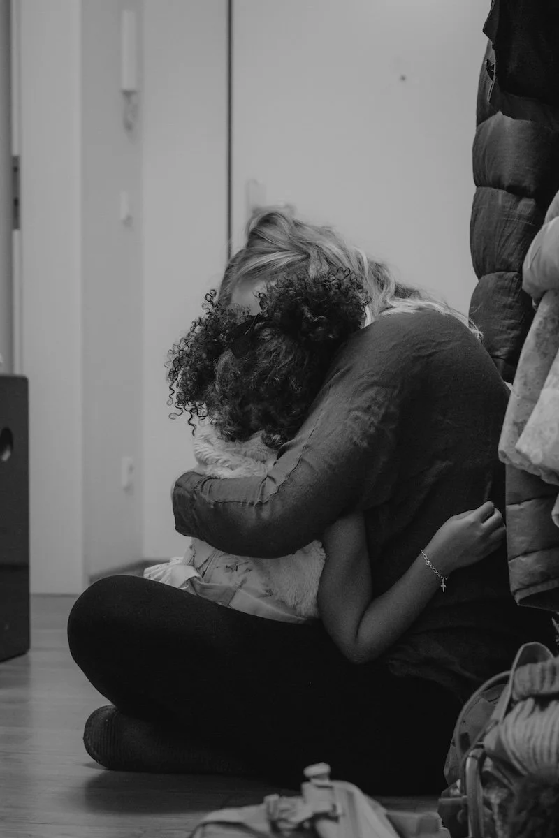 Eine Mama tröstet ihre Tochter und hält sie dabei liebevoll im Arm.