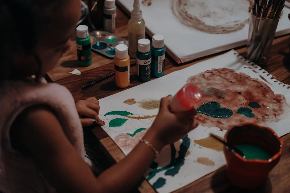 Die Erstgeborene verziert den Plazentaabdruck ihrer kleinen neugeborenen Schwester mit glitzernden Farben.