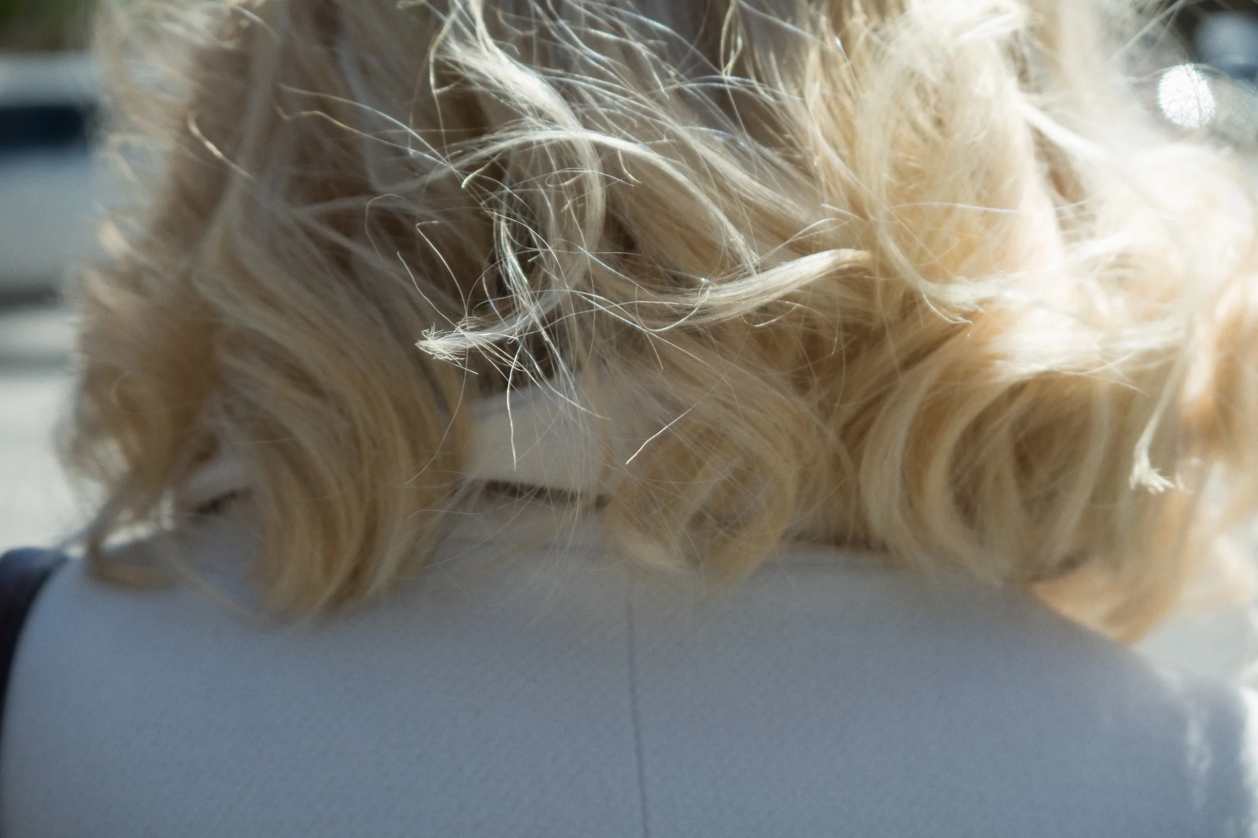 Editorial close-up photograph of a person resting on a white surface, focusing on texture, light, and intimate detail.