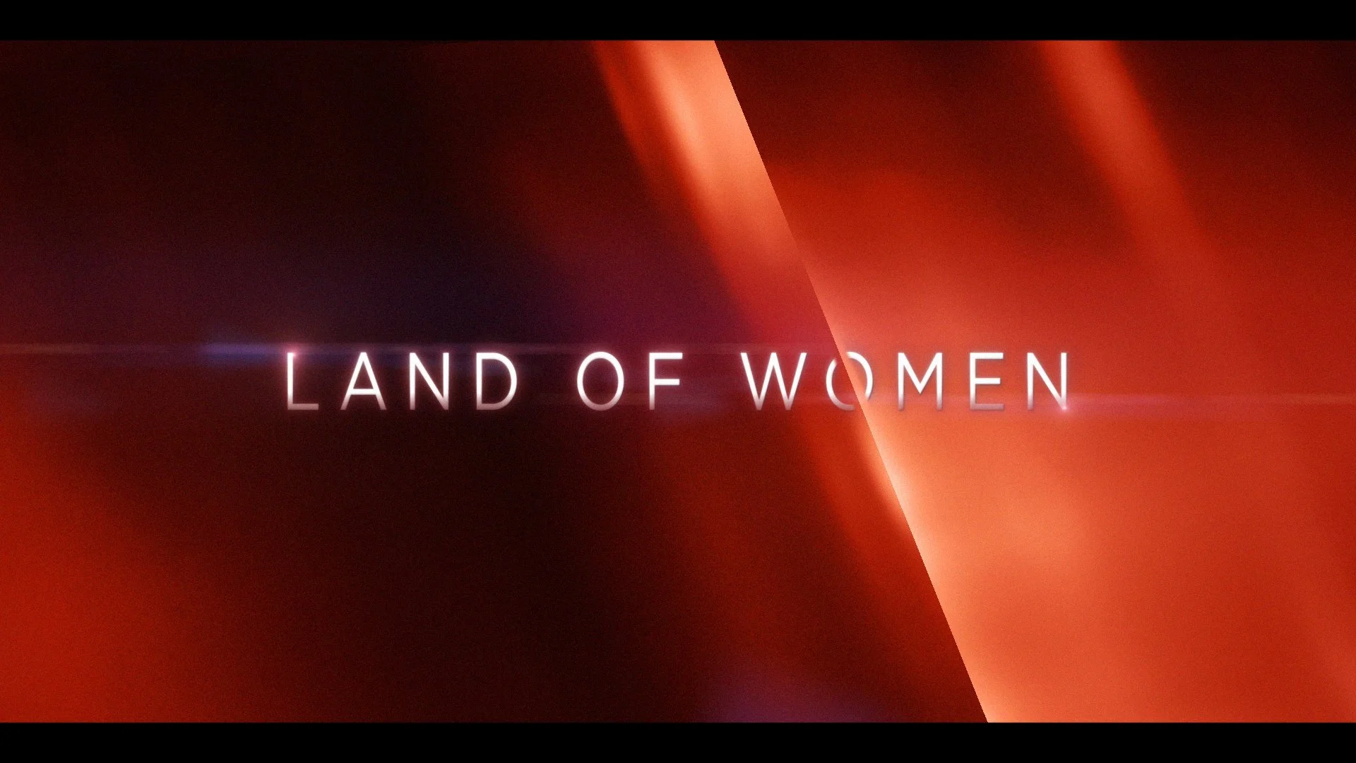 Title screen with the text 'Land of Women' against a background with warm red and orange tones and diagonal light streaks.