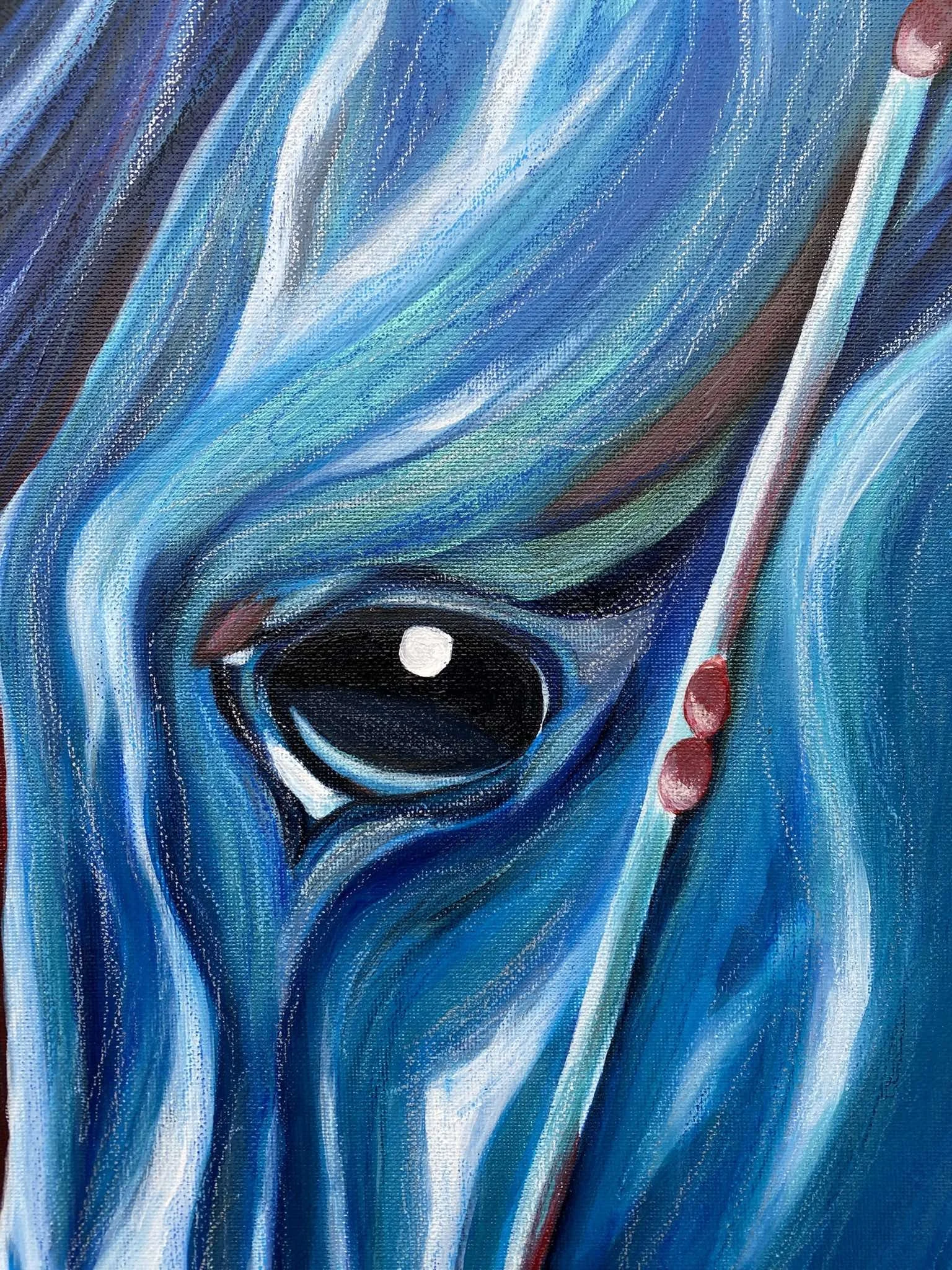 Nahaufnahme eines blauen, gemalten Pferdekopfes mit schwarz glänzendem Auge, detailreichen Pinselstrichen und weißen sowie roten Akzenten.