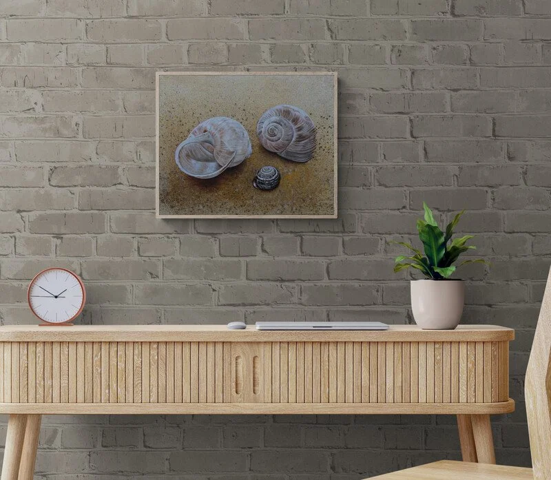 Ein Wandbild mit Muscheln, ein Tisch mit einer Uhr, einer Pflanze in einem weißen Top und einem Computer