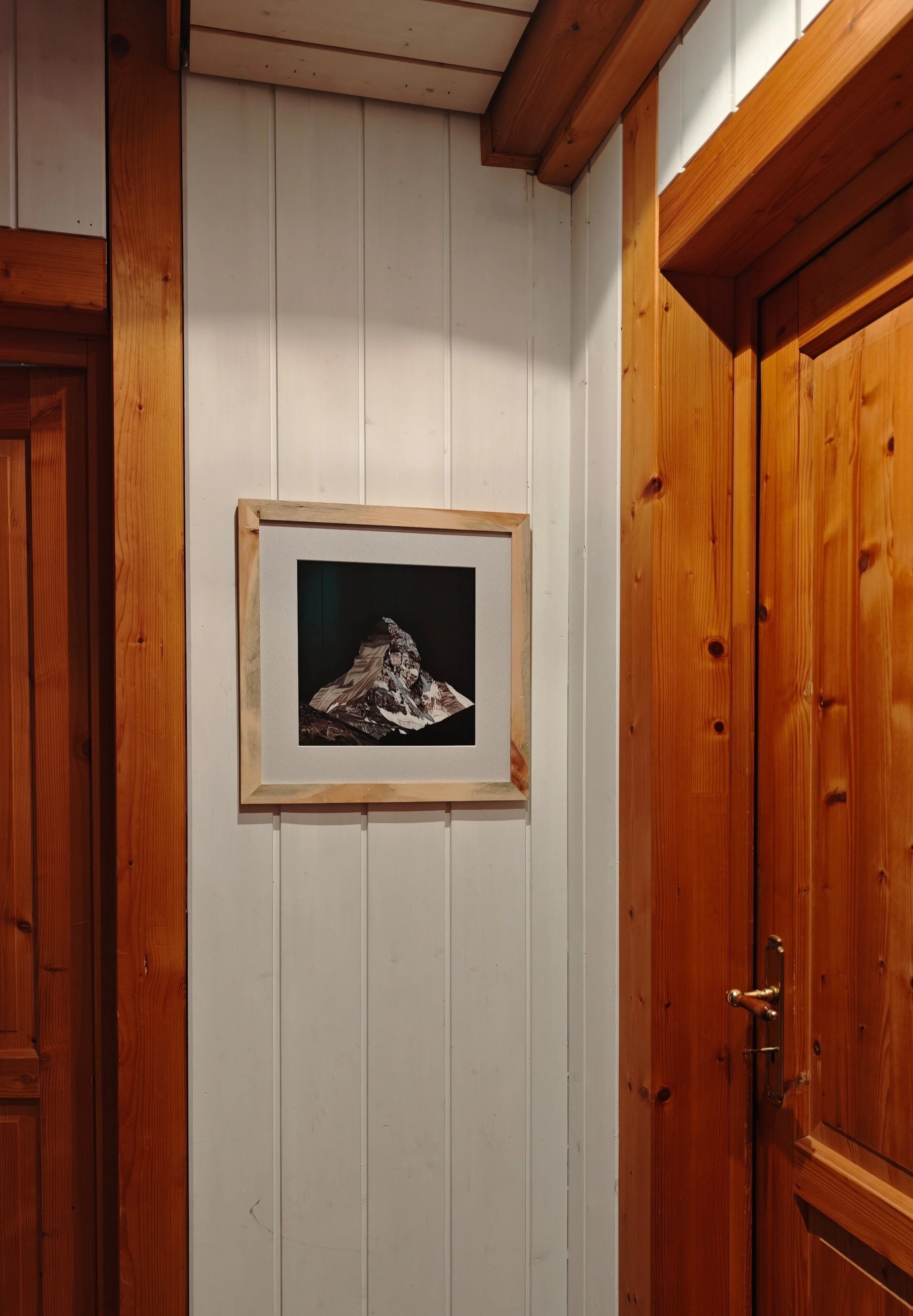 Ein Wandbild einer Berglandschaft, vermutlich das Matterhorn, in einem rustikalen Raum mit Holzvertäfelung.