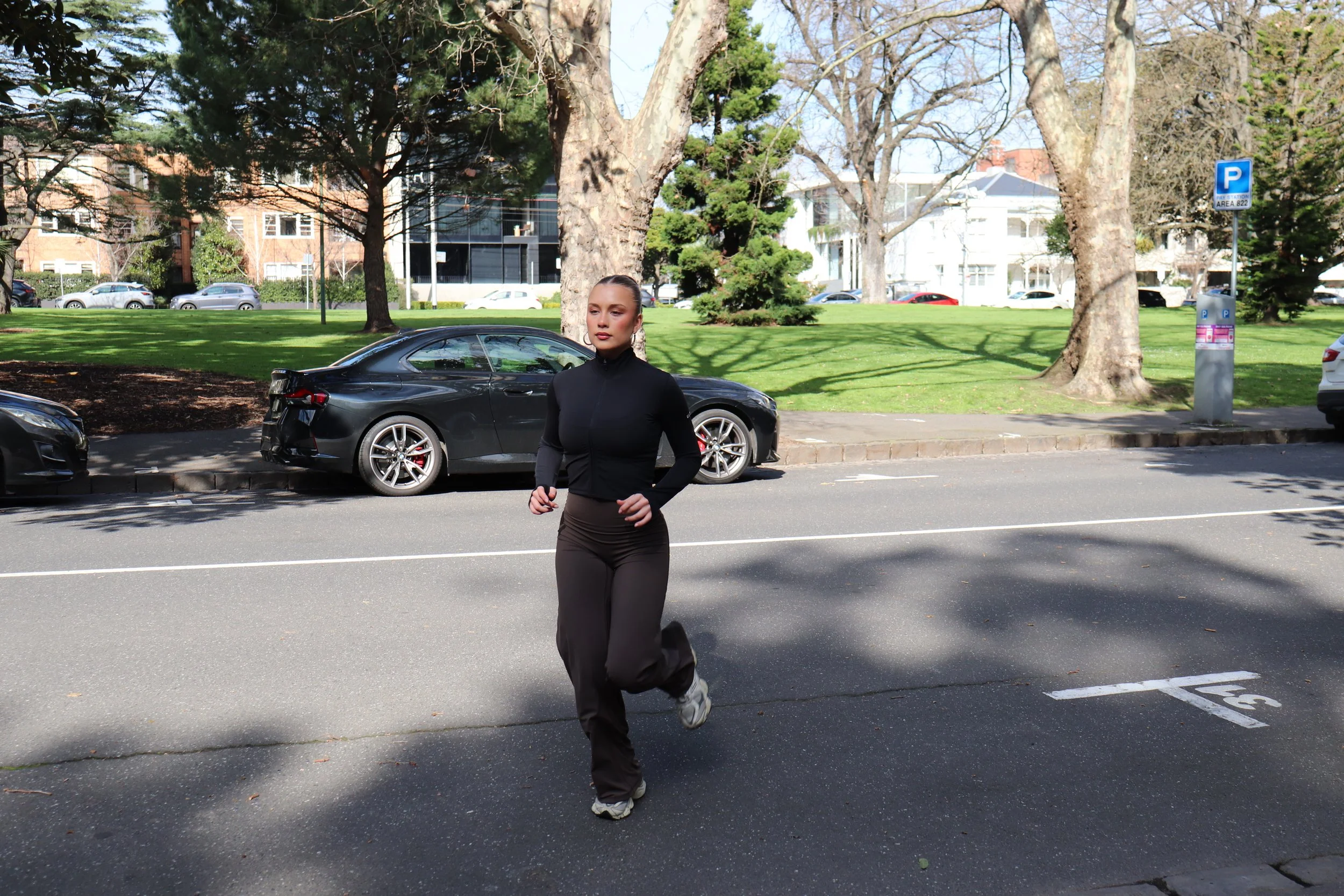 Model running across the road at a park