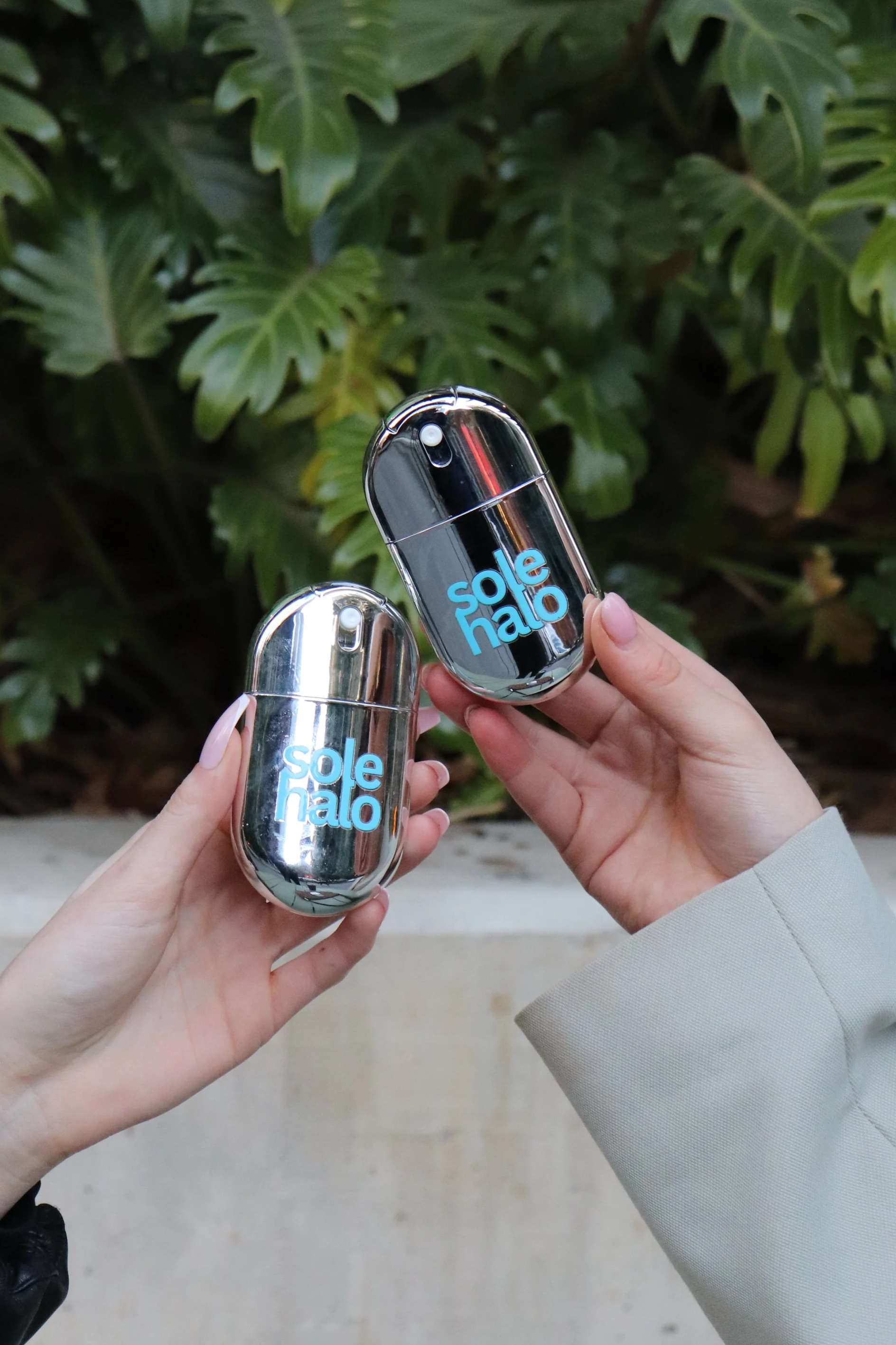 Two hands holding Sole Halo bottles