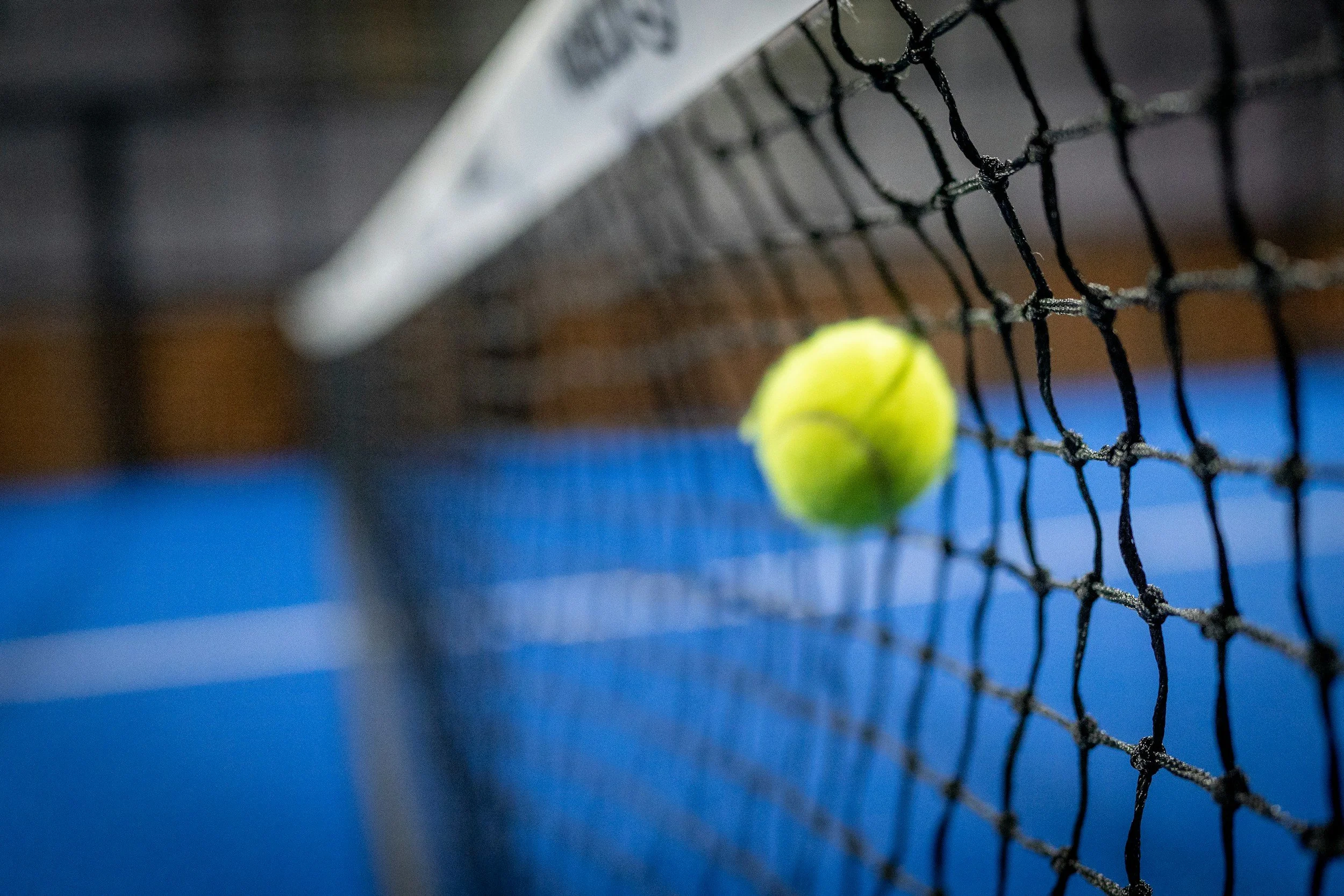 Two tennis rackets and several tennis balls on a blue tennis court.