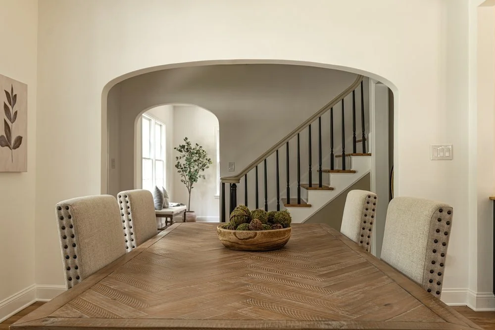 Arched entry of a luxury custom home as a backdrop for a walnut dining table with traditional seating in Georgia