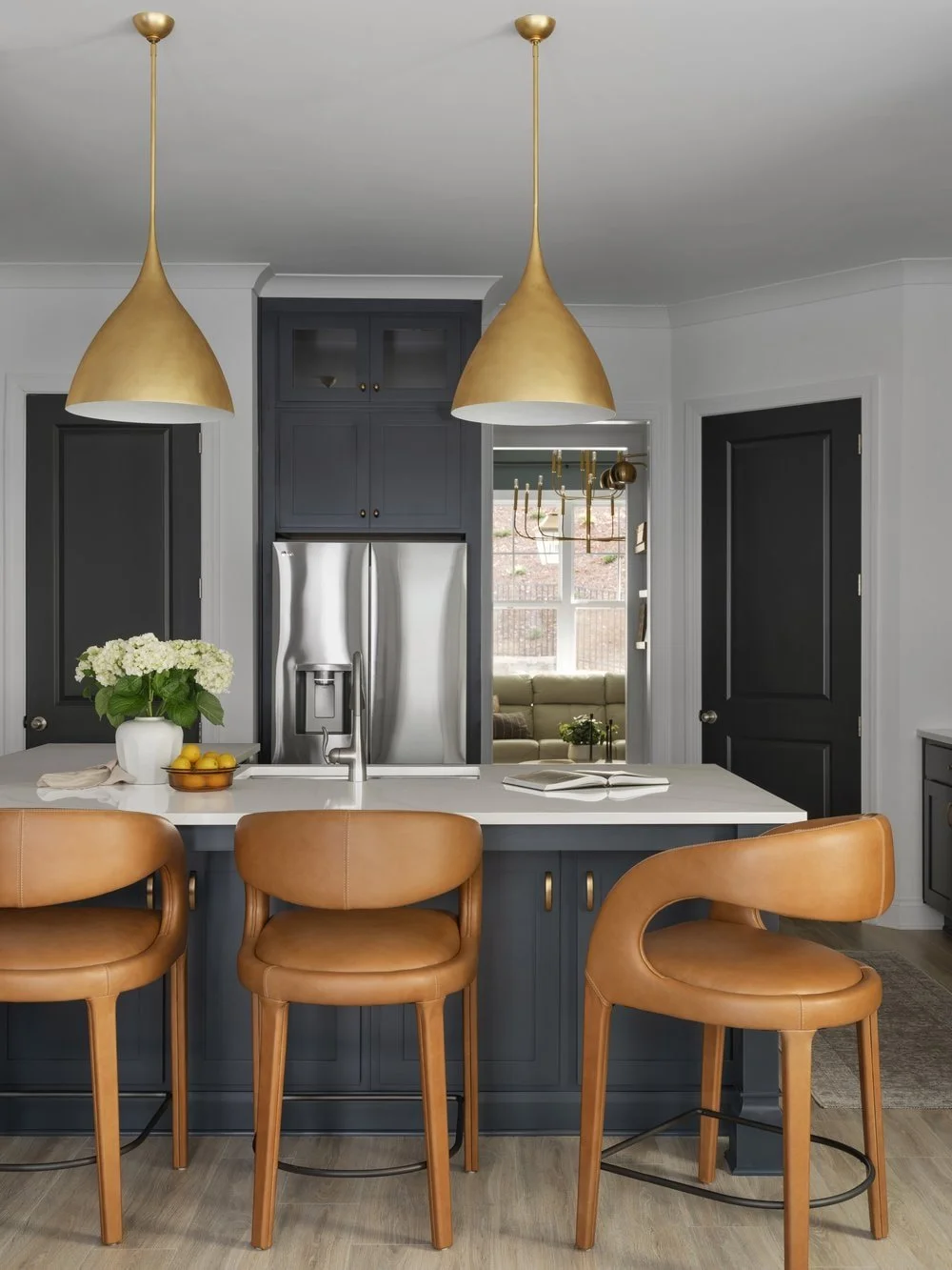 Luxury kitchen backdrop with arched back leather barstools and oversized brass pendants.