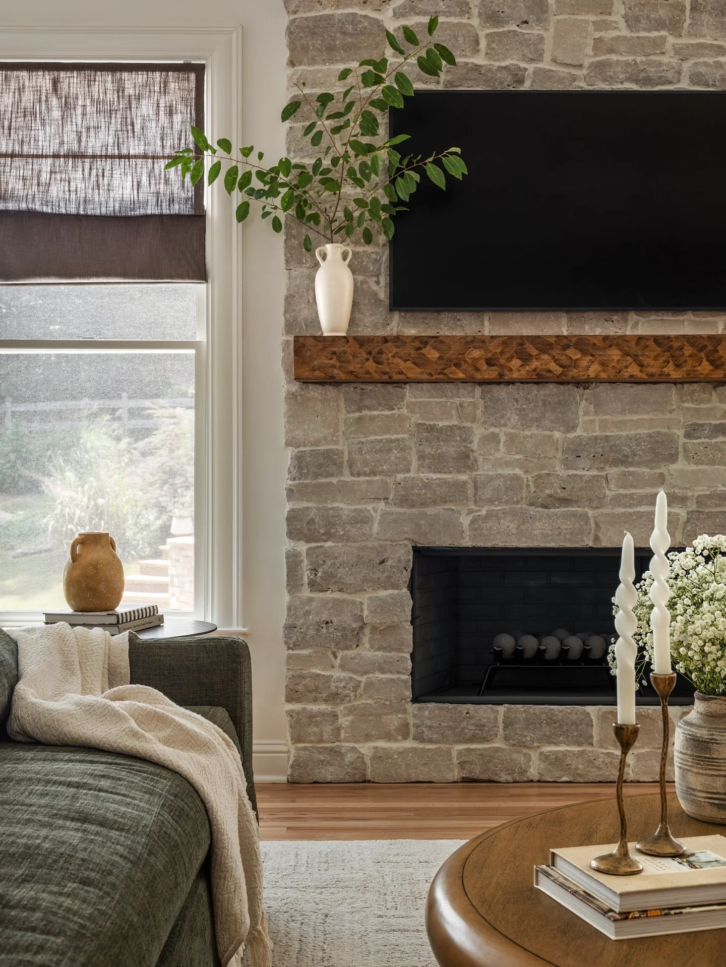 Our designs are all about spaces that feel collected and cozy without being excessive.

This shot captures the perfectly layered warmth and character in our client&rsquo;s living room. From the oak mantle and limestone fireplace to the brown Roman sh