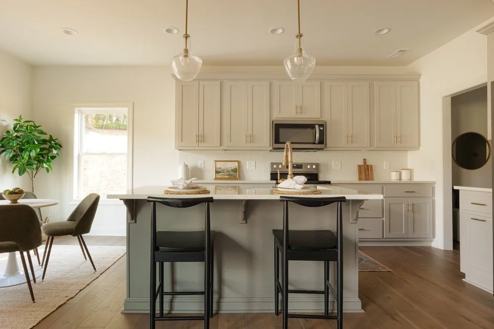 Full view of custom kitchen in modern mountain home with two toned cabinetry, round breakfast nook area, and black arched back barstools.