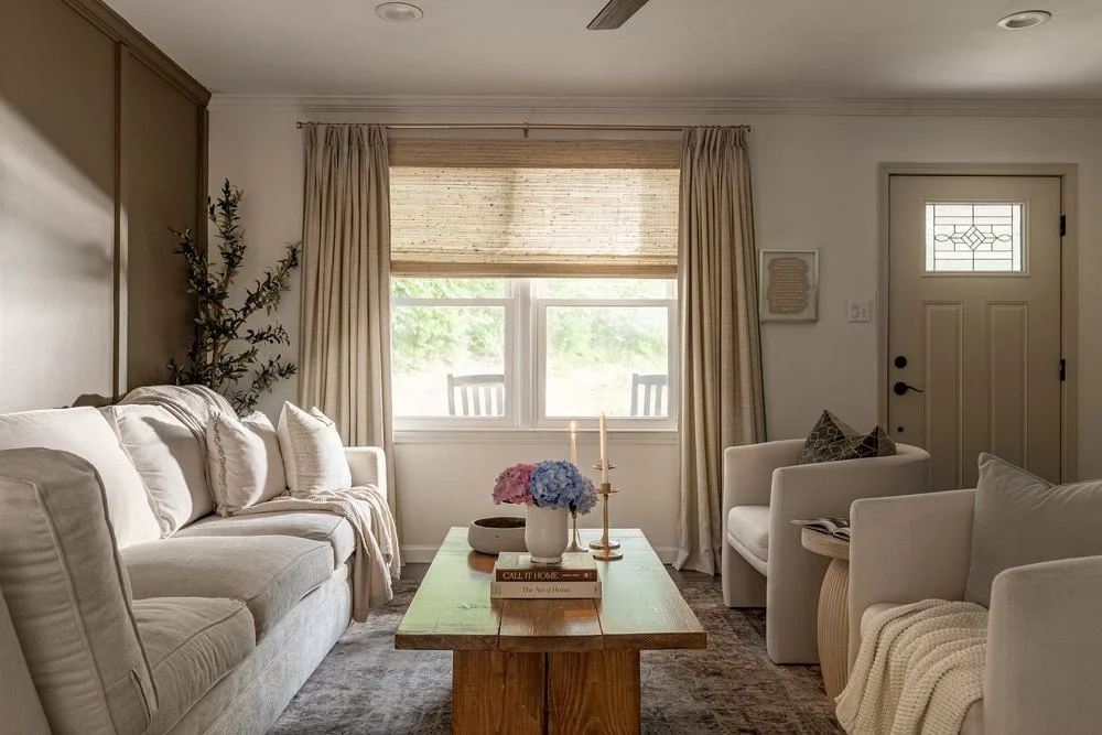 Timeless living room design in Athens GA home with neutral furnishings, wooden side tables, and layered window treatments
