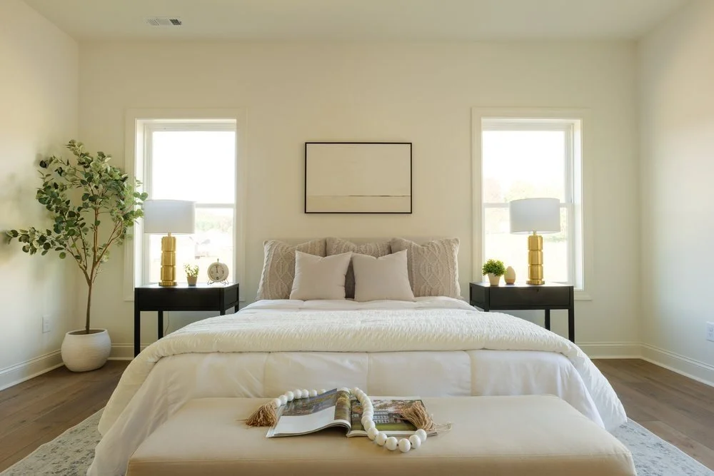 Master Bedroom design neutral organic aesthetic anchored with two black nightstands and mountain scene centered between two windows.