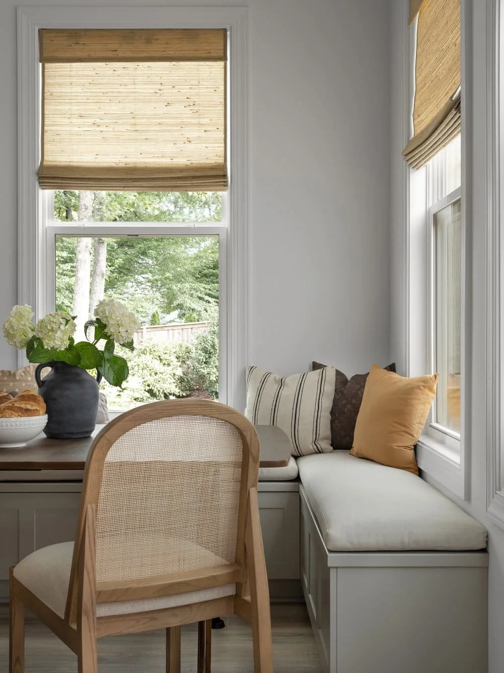 Custom banquette seating for family breakfast nook with bamboo roman shades in a modern transitional design