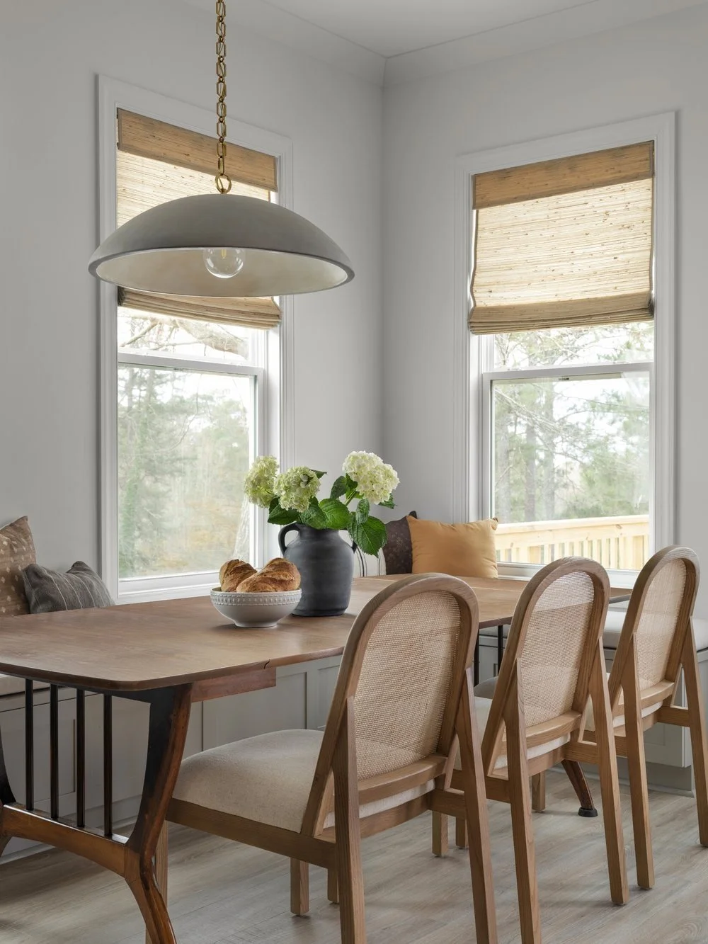 Breakfast Nook designed in georgia family home with Roman shades, a custom seating banquette, and a concrete pendant light.