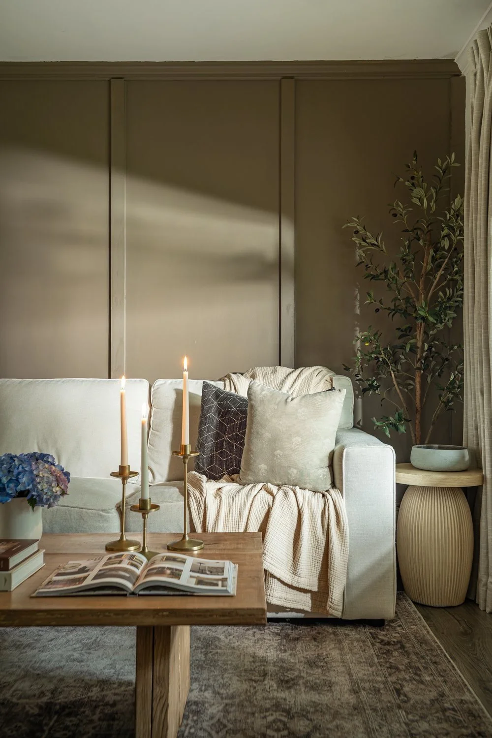 Half of living room sofa in Athens based home with brown board and battan accent wall and modern organic touches