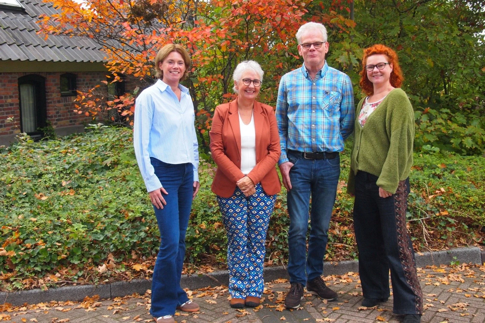 Vijf mensen poseert voor een foto, in een kamer met muzieksouvenirs op de muur."