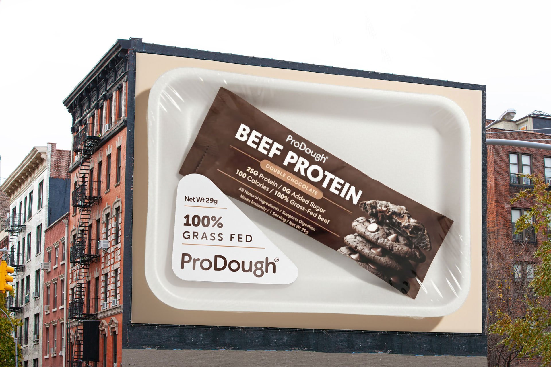 ProDough Beef Protein packet on a giant butcher's meat tray wallscape billboard with "100% Grass Fed" label.