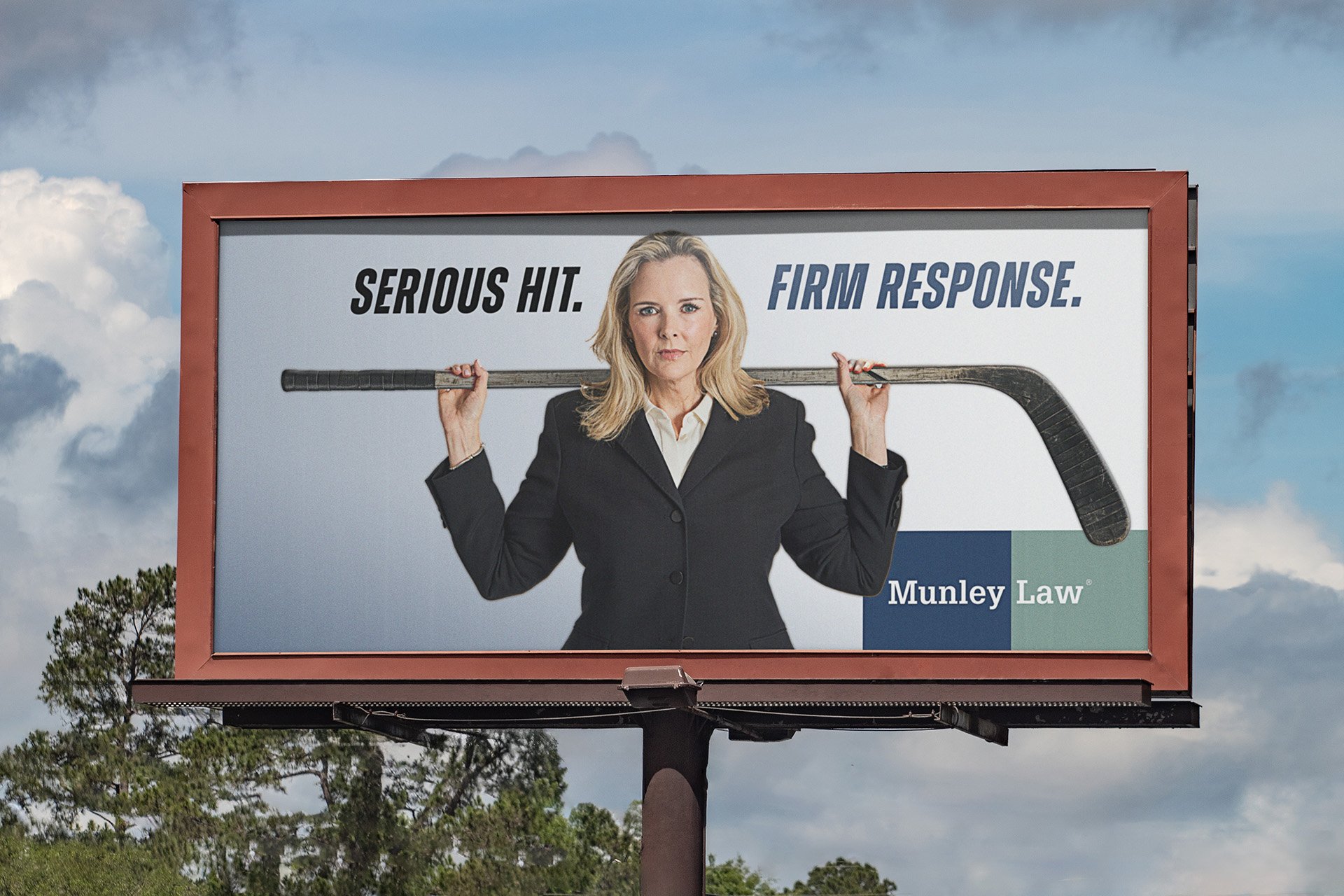 Billboard advertisement for Munley Law featuring a woman in a black suit holding a hockey stick over her shoulders, with the text 'Serious Hit. Firm Response.'