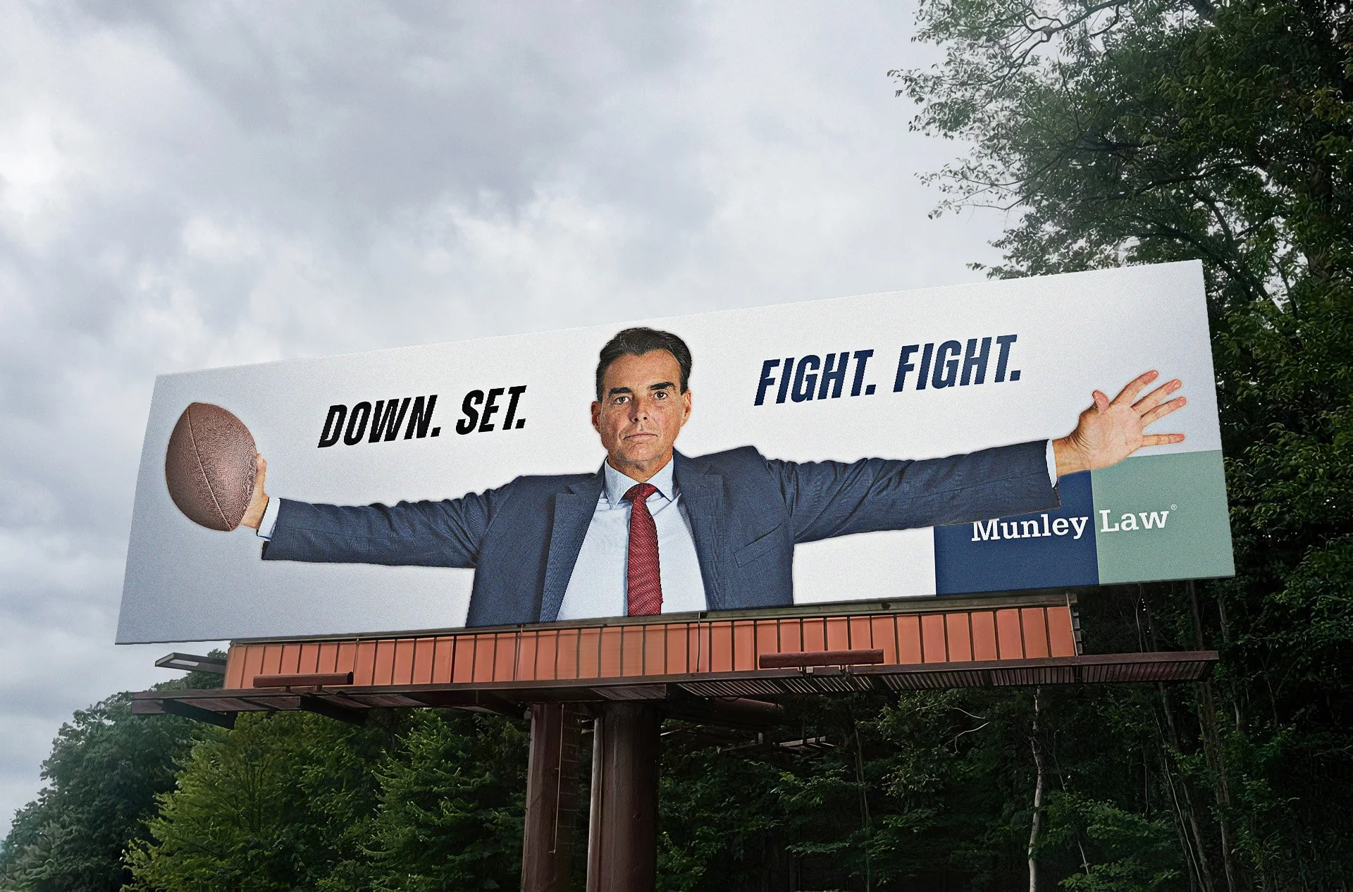 Political billboard featuring a man in a suit holding a football, with text saying 'DOWN. SET. FIGHT. FIGHT.' and the logo 'Munley Law'.