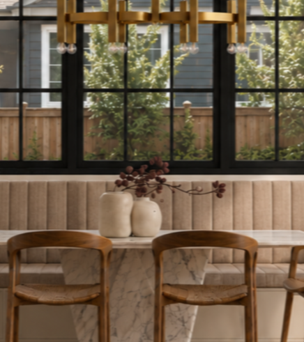 SK Studio Design - Custom Interior of a dining area banquette with a marble table, two wooden chairs, and a beige upholstered bench.