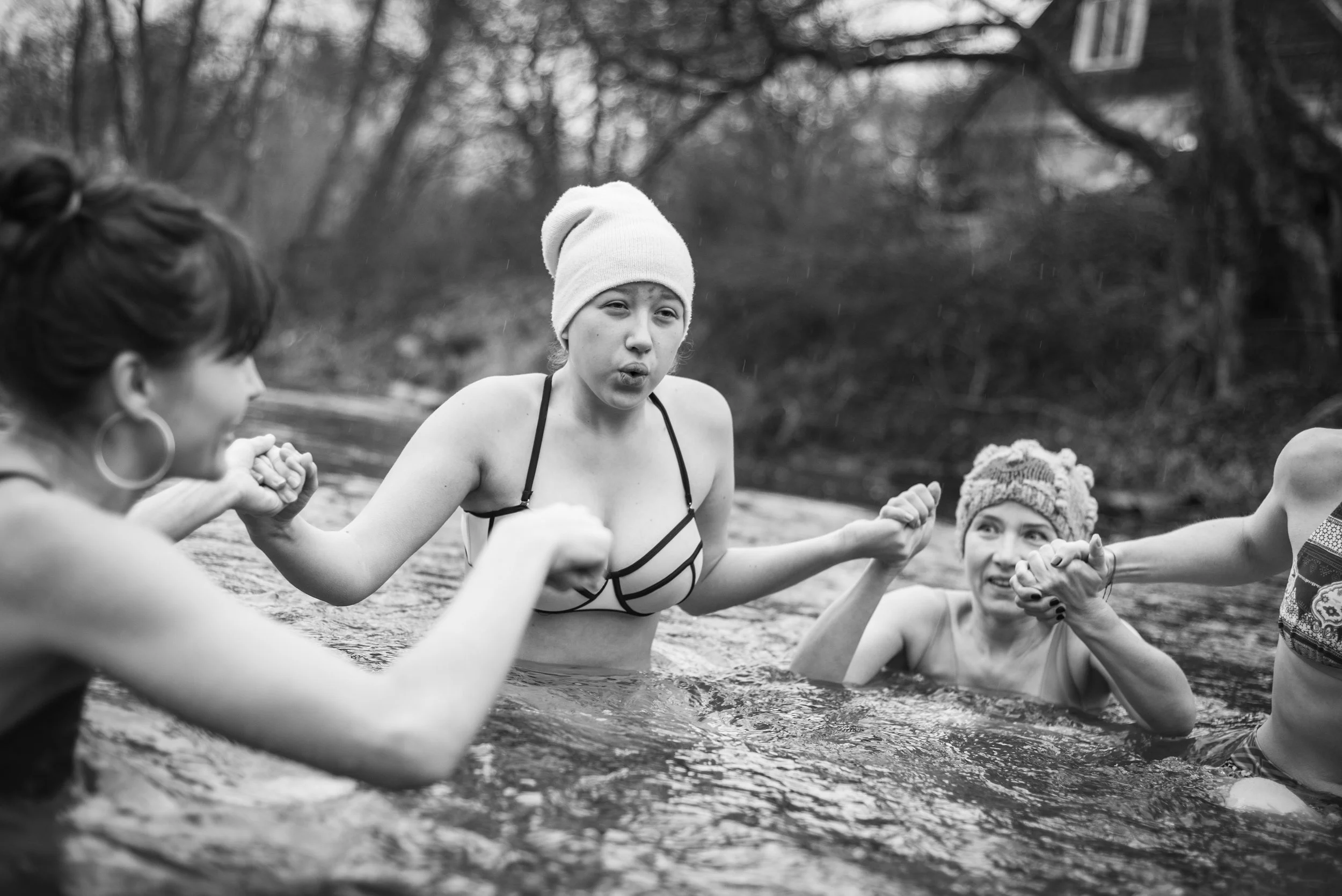 Participants holding hands and breathing together in cold river water during a Wim Hof Method session