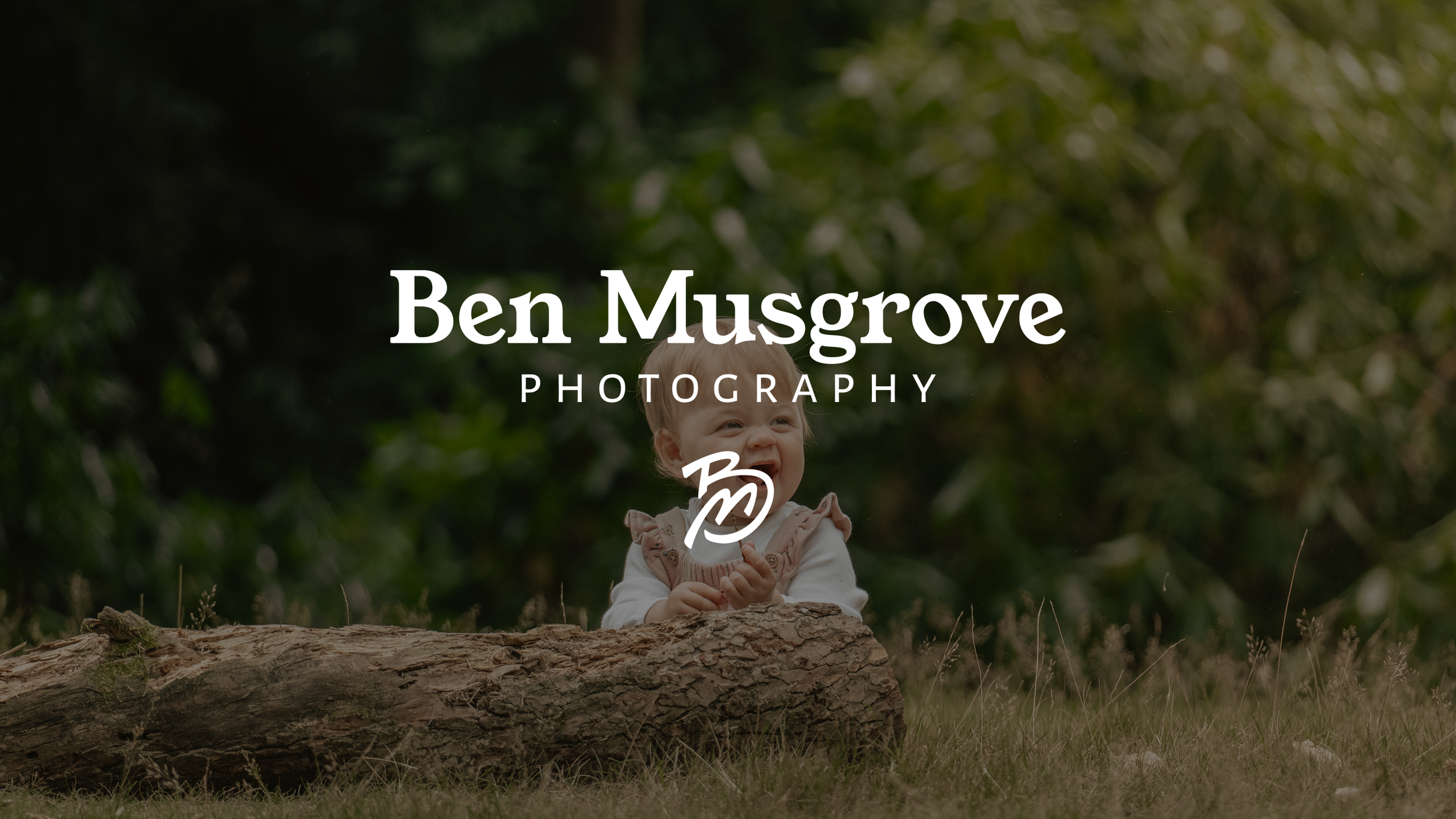 Young girl sitting on a log outdoors in a forest with lush green trees in the background. Portait photography from en Musgrove Photography.