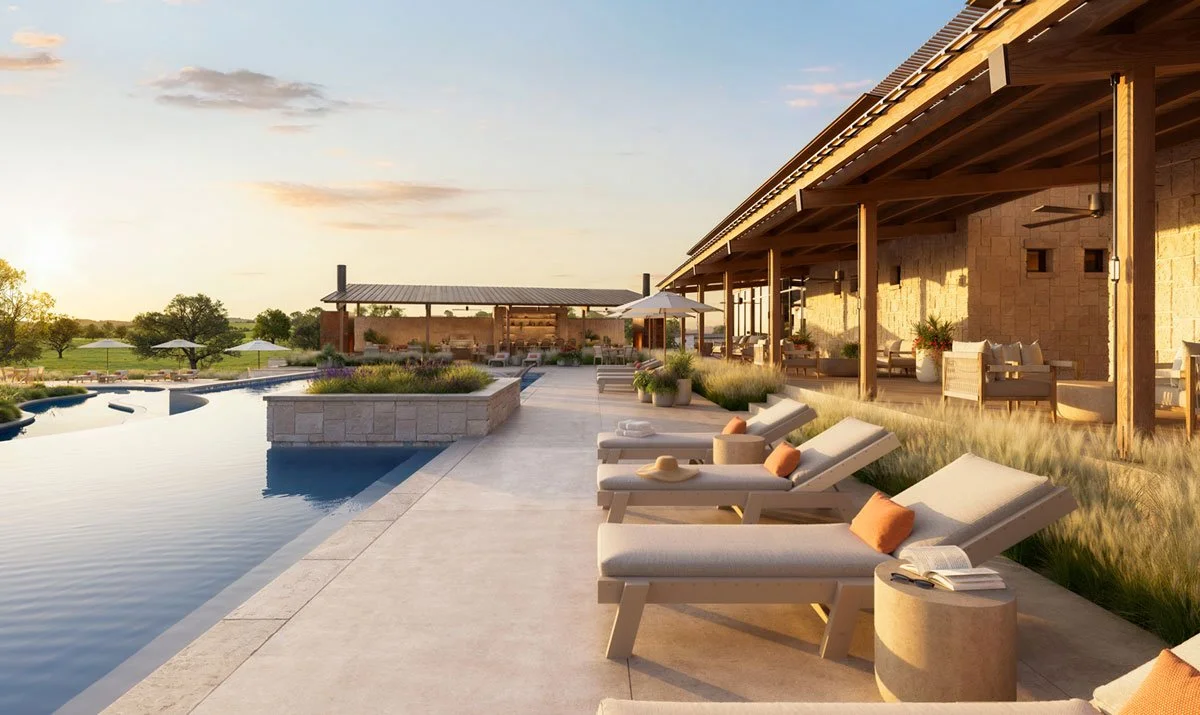 Luxury outdoor swimming pool with lounge chairs and umbrellas beside a modern home at sunset in Hye Springs Ranch in Fredericksburg TX.