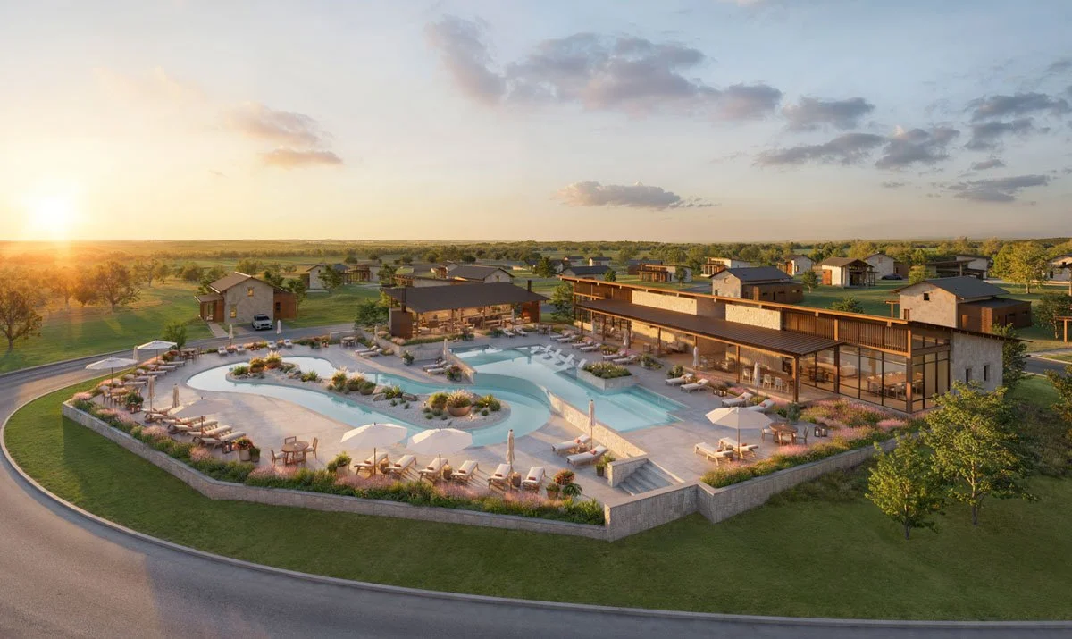 A modern outdoor pool area with lounge chairs and umbrellas, surrounded by a low wall, in a residential community during sunset.