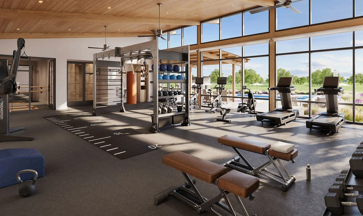 Well-lit gym with large windows, various exercise machines, free weights, and workout equipment in Hye Springs Ranch in Fredericksburg TX.
