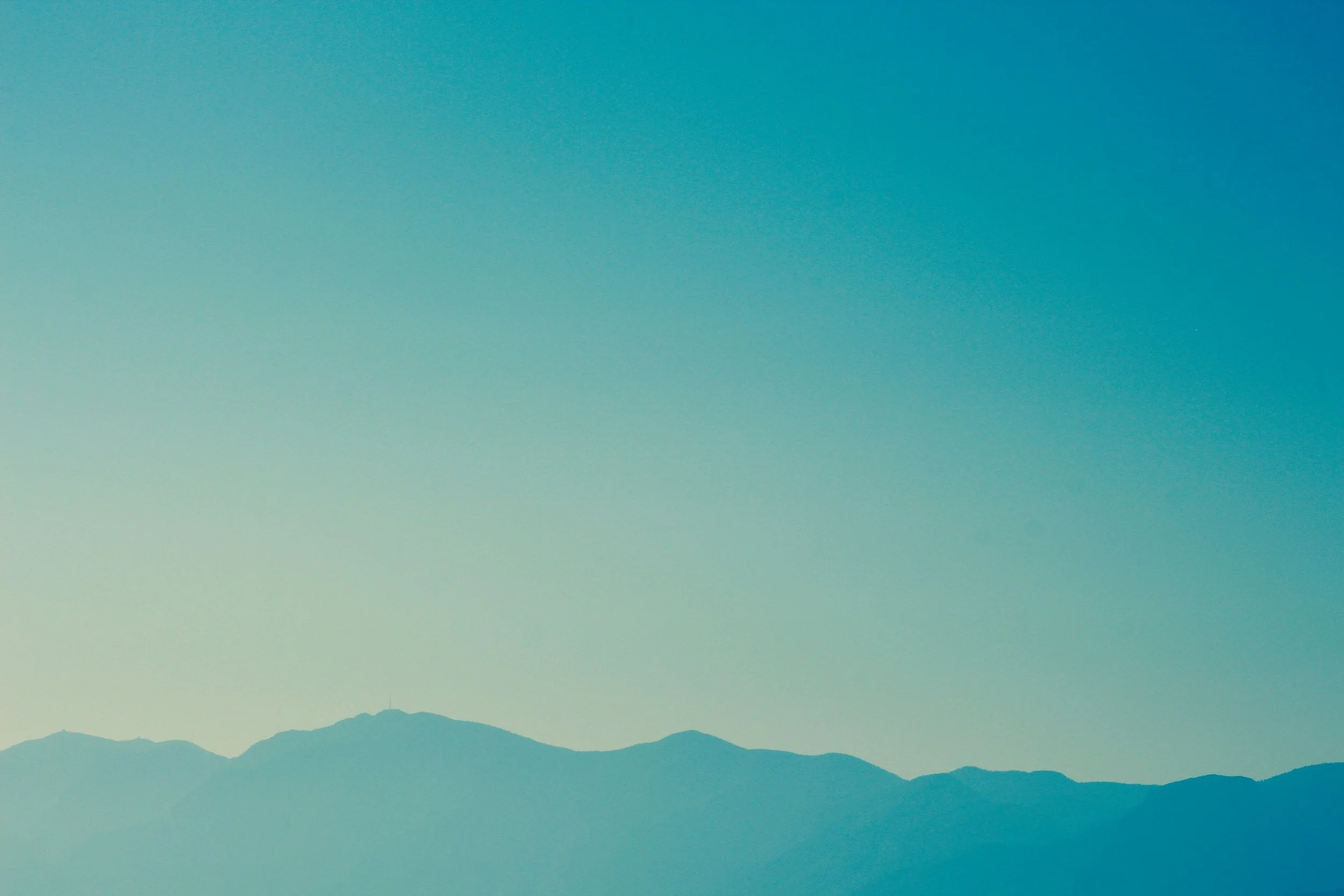 Silhouette of distant mountains against a clear blue sky.