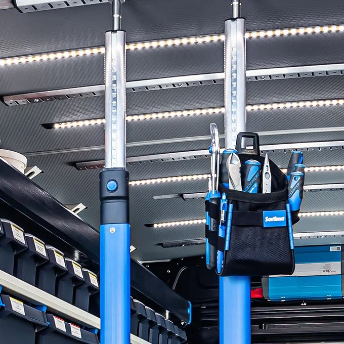 Retail store aisle with electric shopping cart featuring a tool bag containing screwdrivers and pliers.