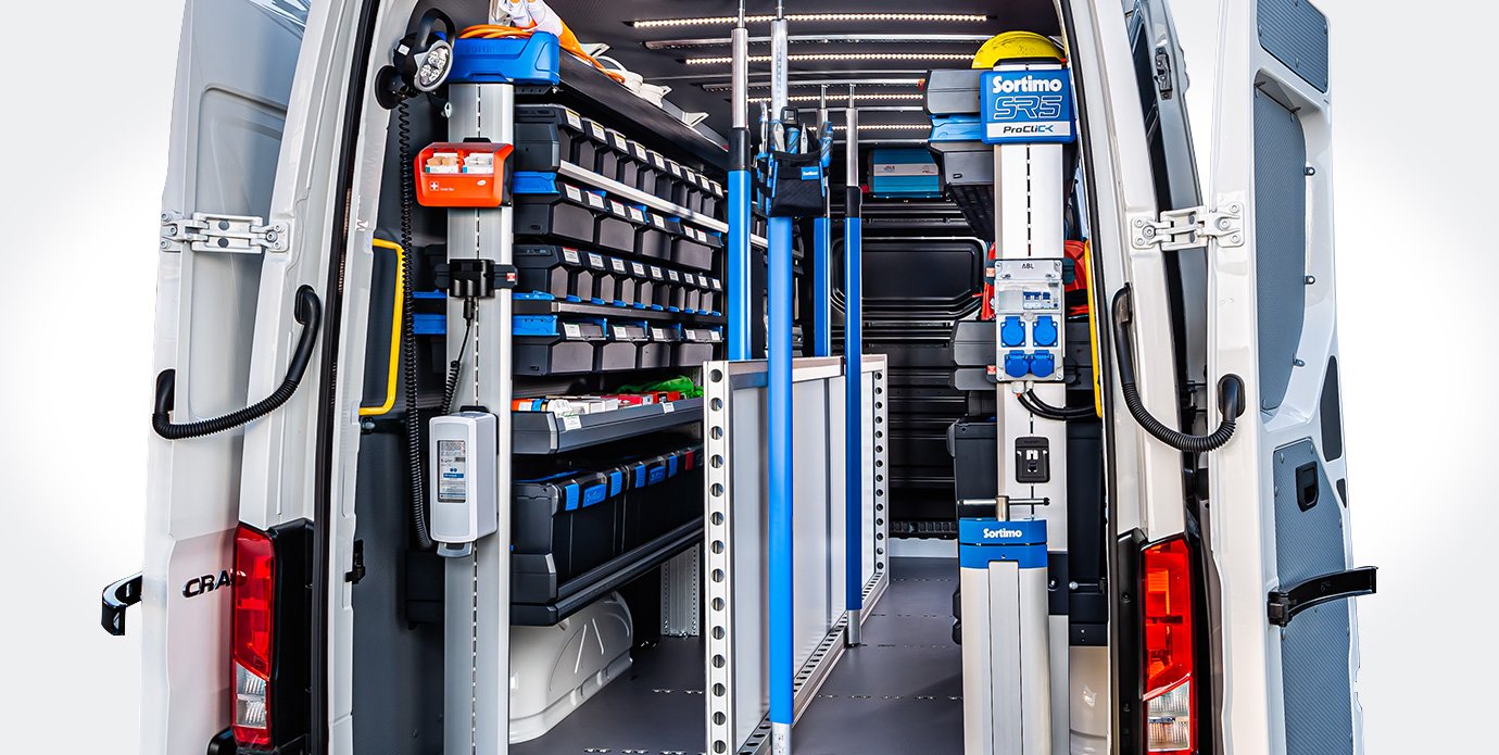 Inside of a service or utility van organized with shelves, bins, and tools for repairs or maintenance.