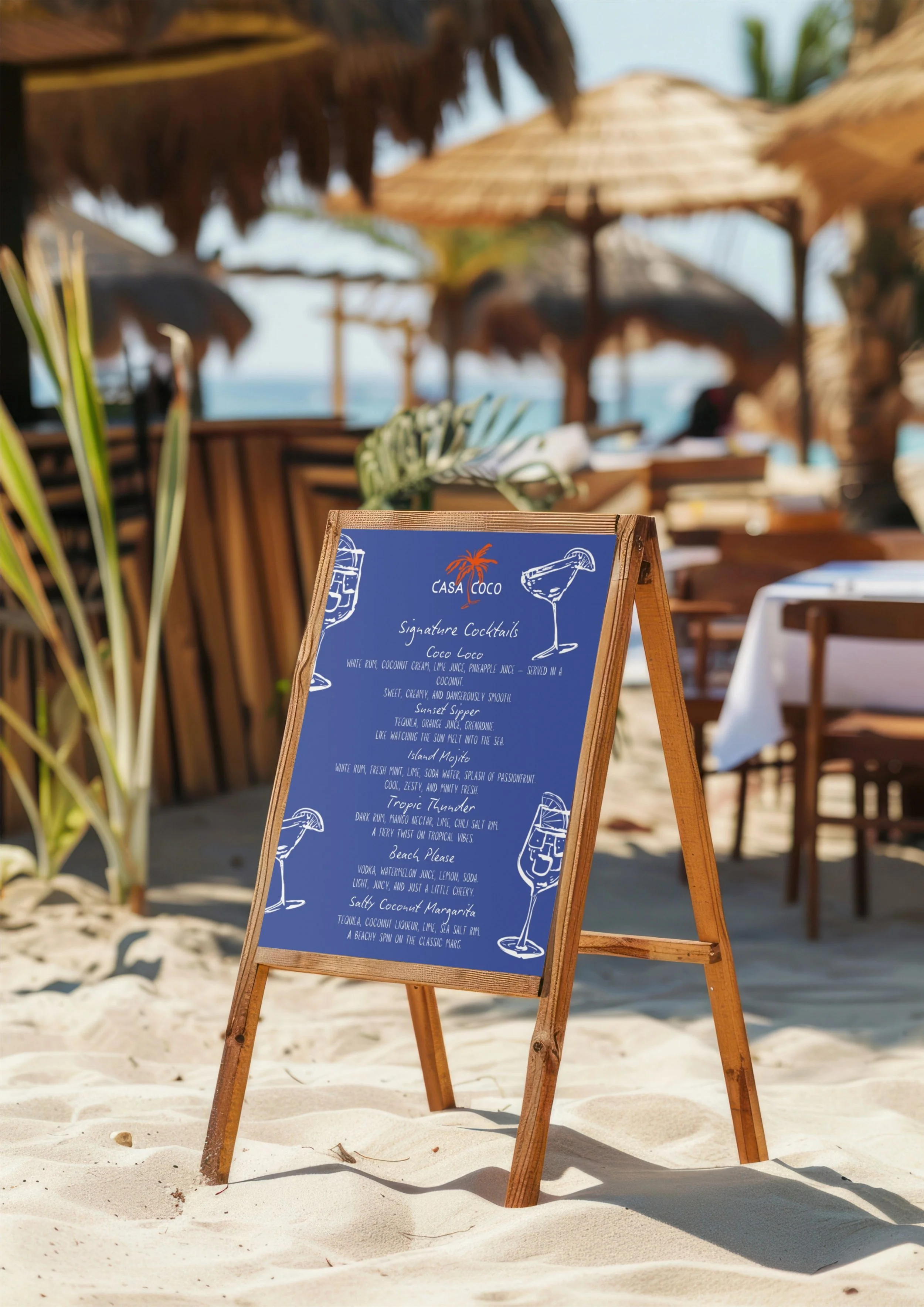 Blue outdoor menu board on a wooden stand on sandy beach, with straw umbrellas and beach chairs in the background.