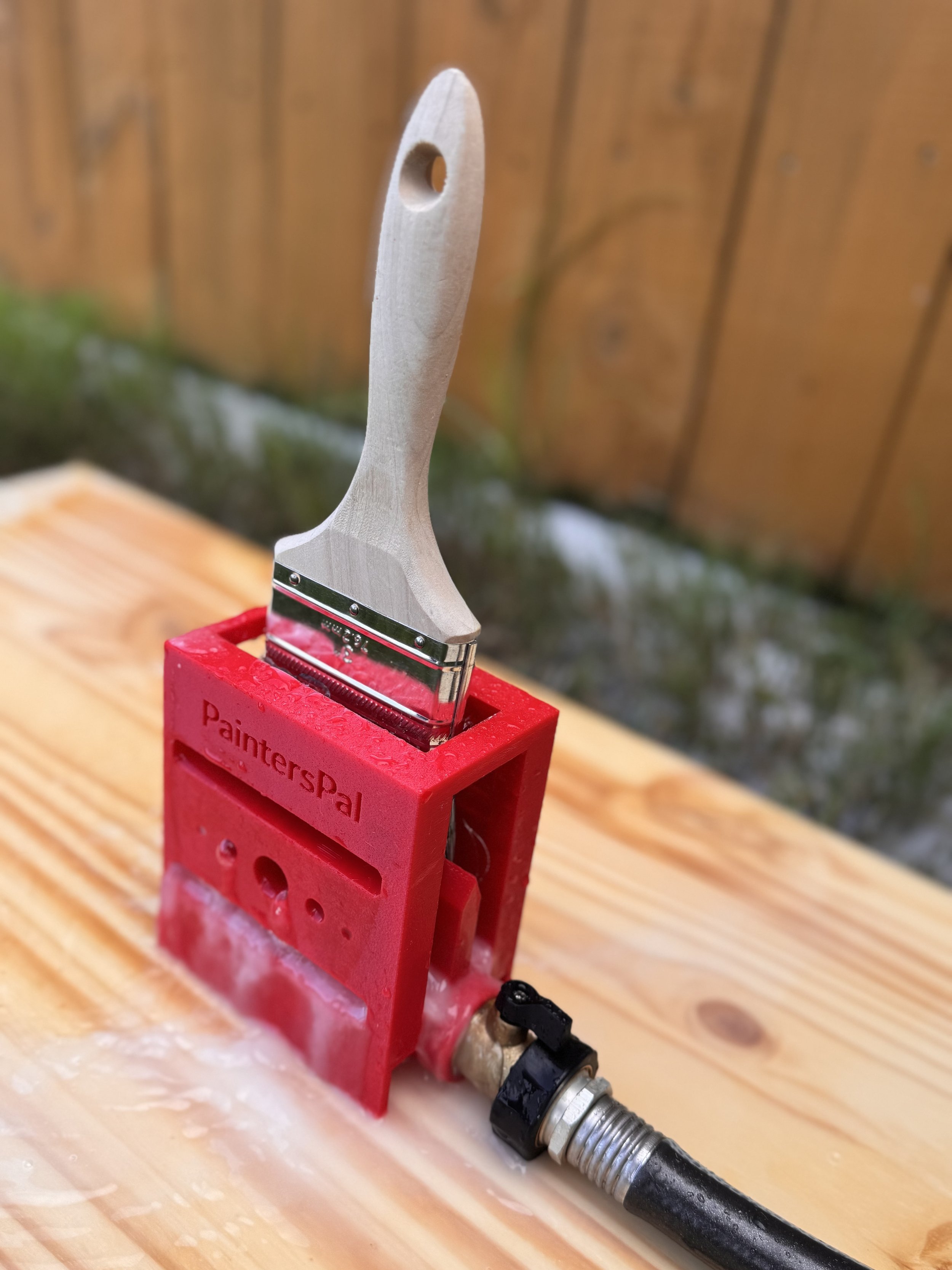 A 3 inch paintbrush in a paintbrush cleaning tool garden hose attachment. a paintbrush being effectively cleaned with a Painter's Pal