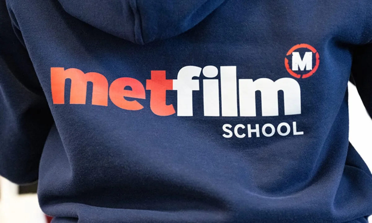 Close-up of a navy blue hoodie with the logo 'met film SCHOOL' printed on it in red, white, and black letters.