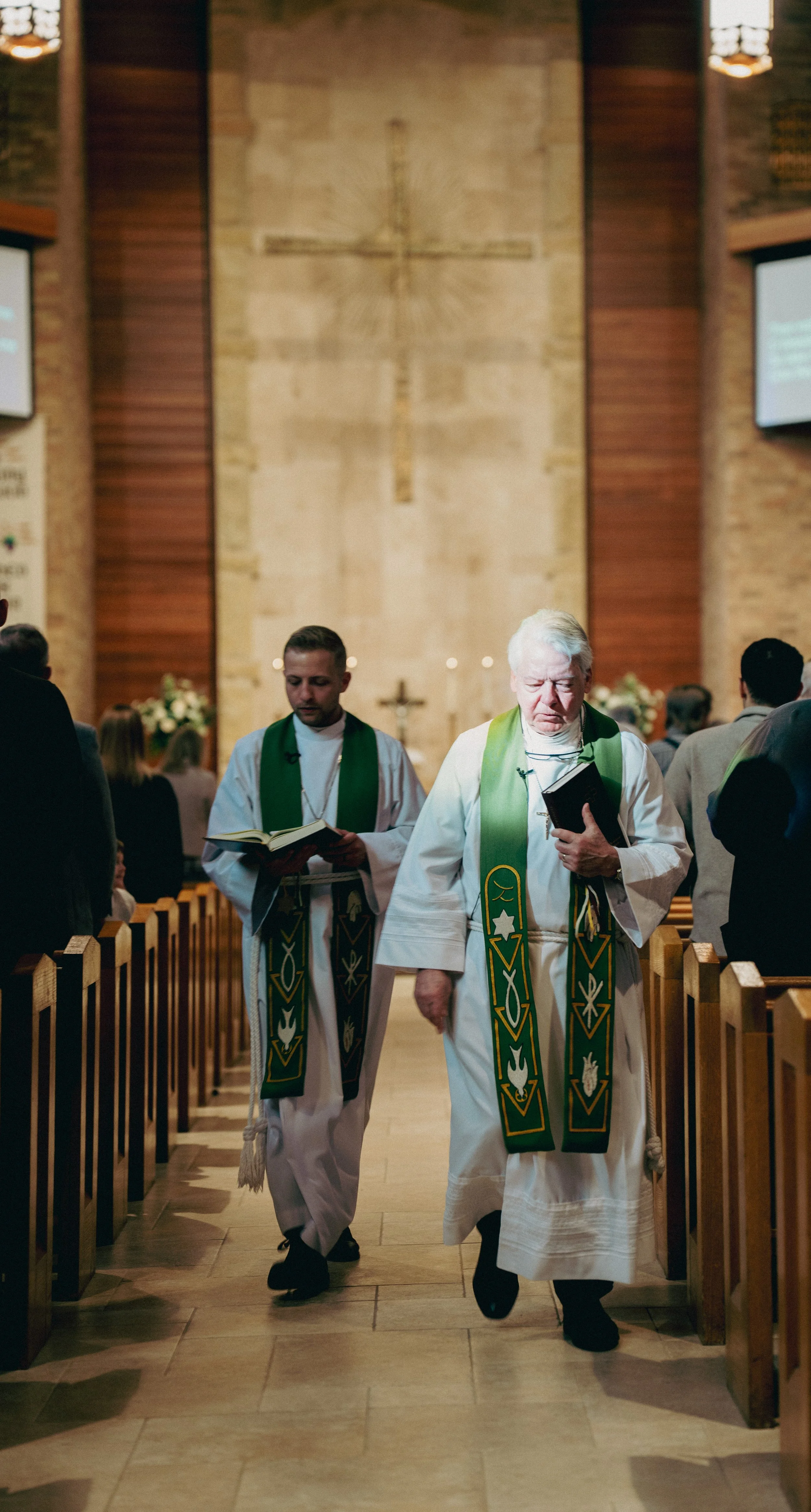 Church clergy walking down the aisle during a service, with an altar in the background and congregation on either side.