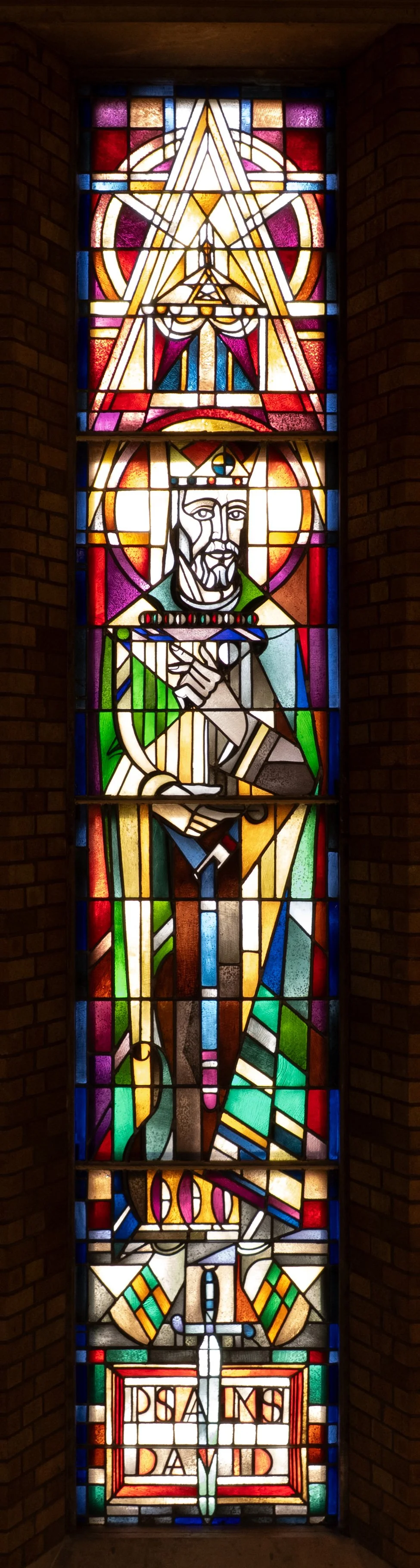 Stained glass window depicting a crowned king holding a sword, with religious and heraldic symbols, and the name 'St. David' at the bottom.