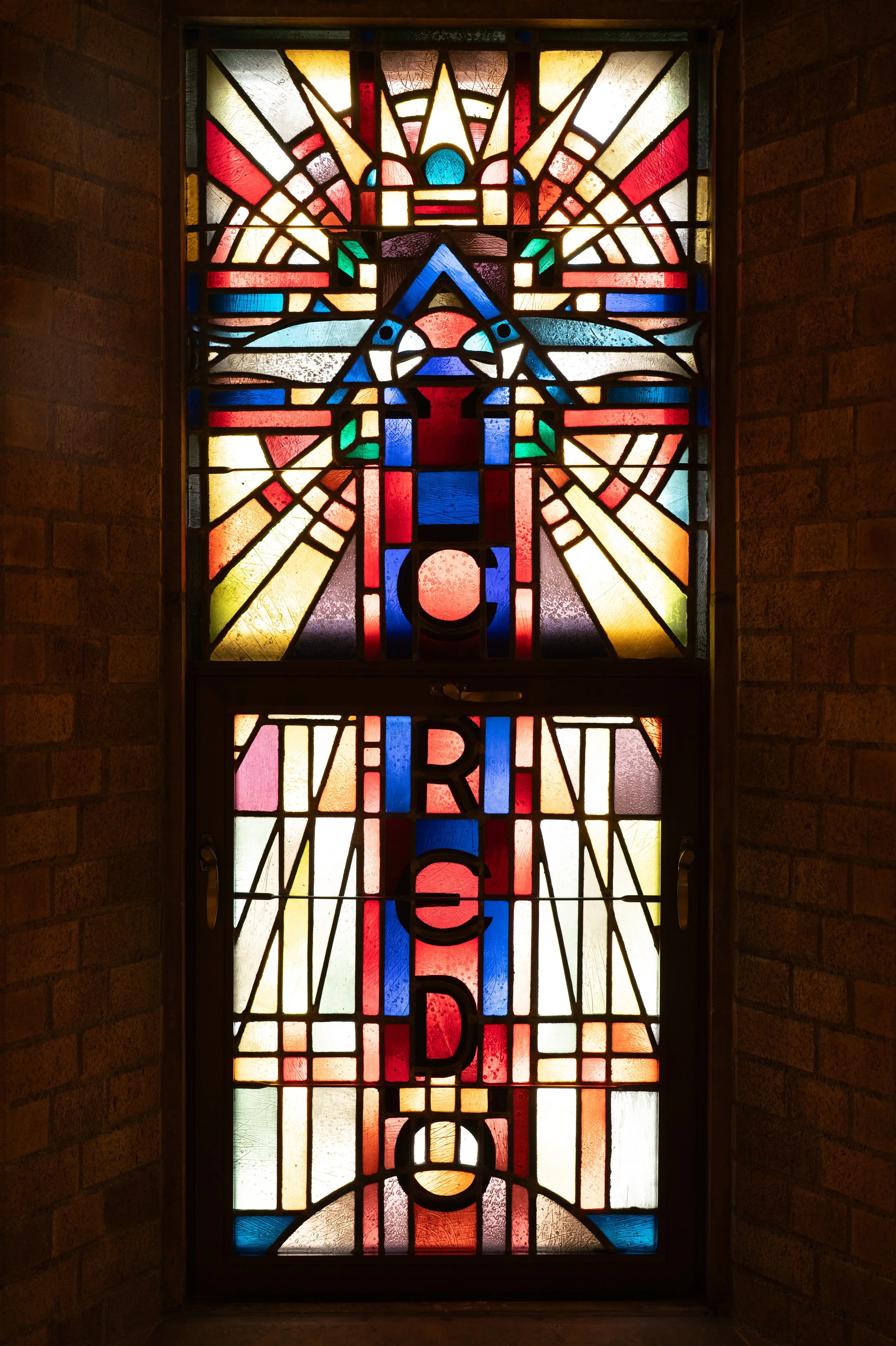 Colorful stained glass window with religious and spiritual imagery, including a depiction of a cross and radiant light, with the words 'CREDO' in bold letters.