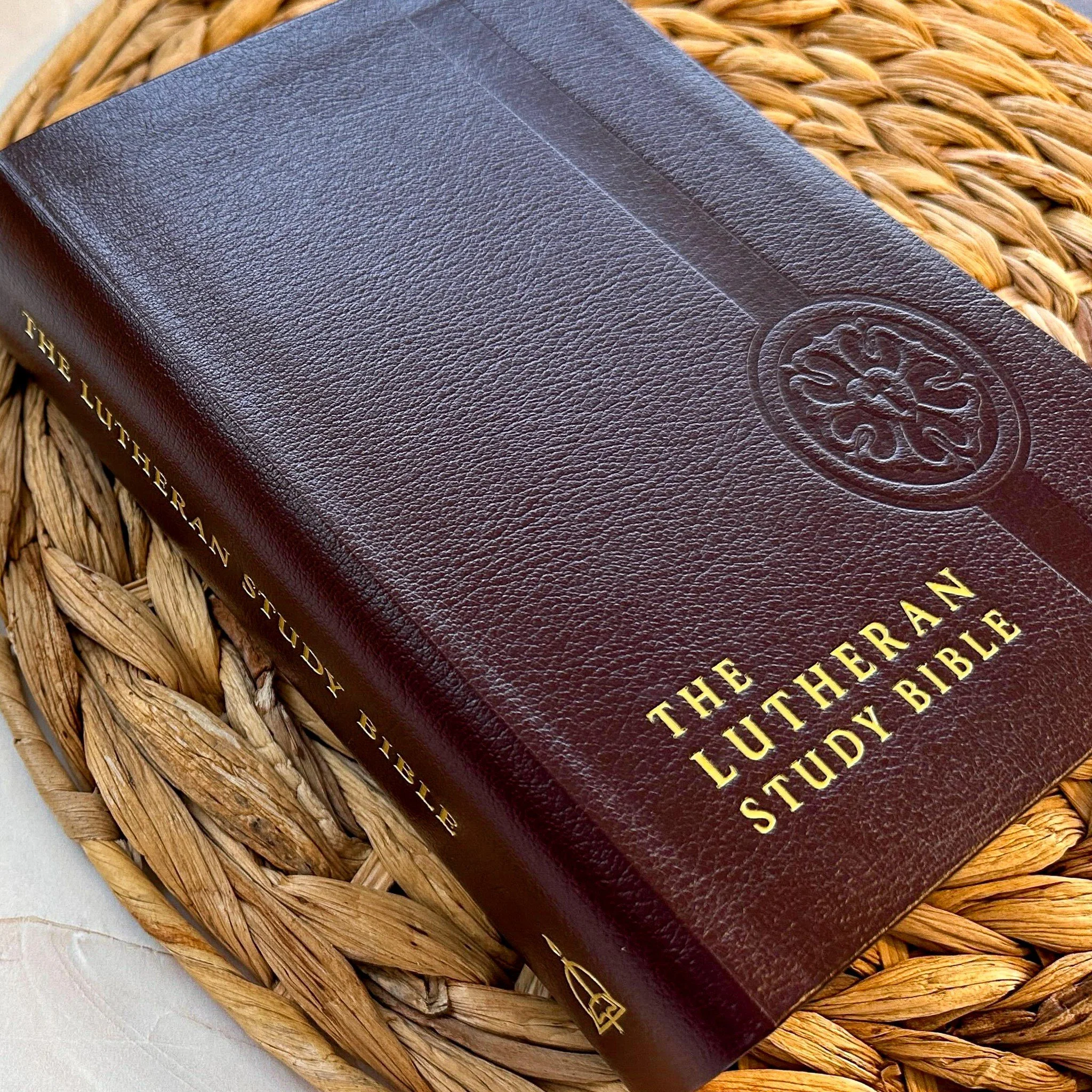 A hardcover book titled 'The Lutheran Study Bible' with a brown textured cover and gold lettering, resting on a woven basket.