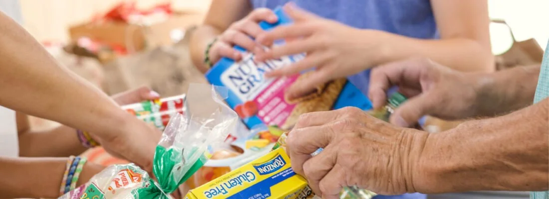 People reaching for snacks and candy at a food drive or gathering.