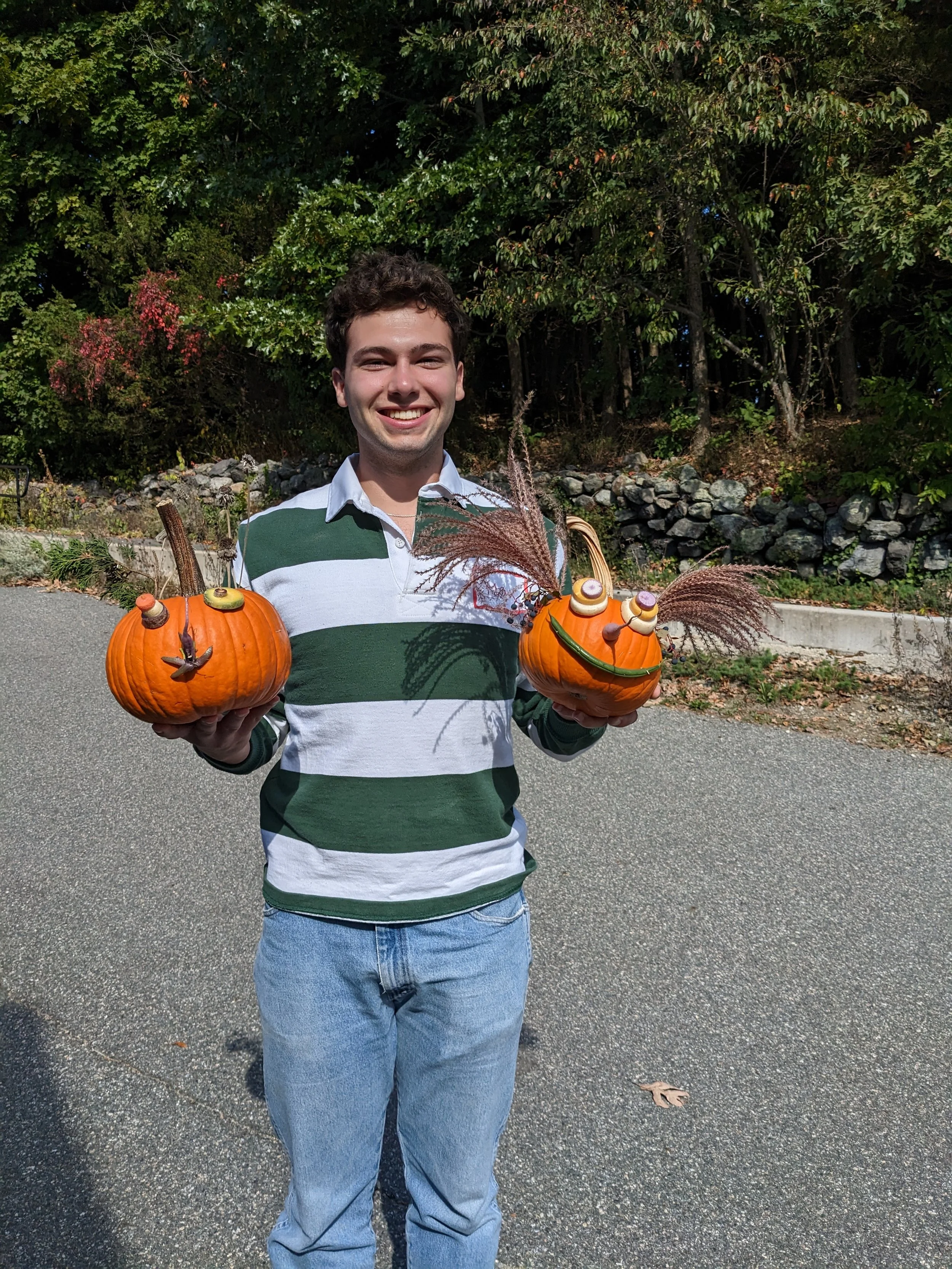 A volunteer holding decorated pumpkins in each hand