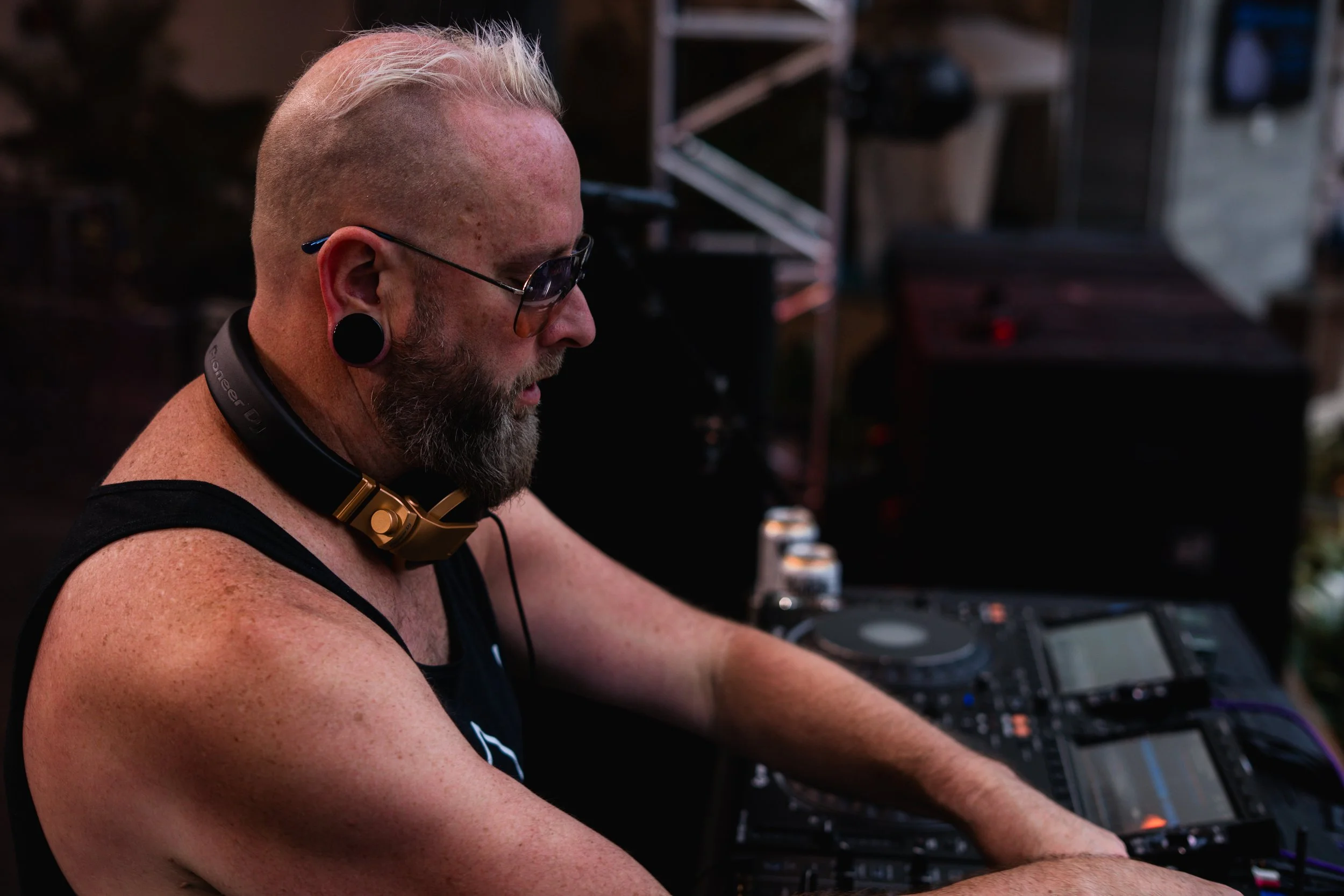 A man with sunglasses and large ear gauges DJing at an outdoor event.mattb artist prominent dj grand rapids ready for bookings and big festivals, artist, founder remedy collective djs sound production lighting mattb tours festival wawye oasis pauly d